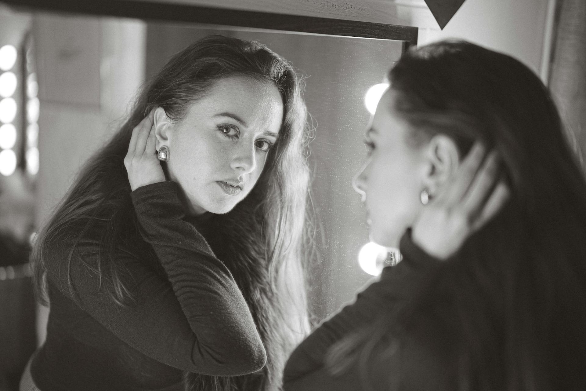 A woman quietly studying her reflection representing the first-impression presence of the 1st house