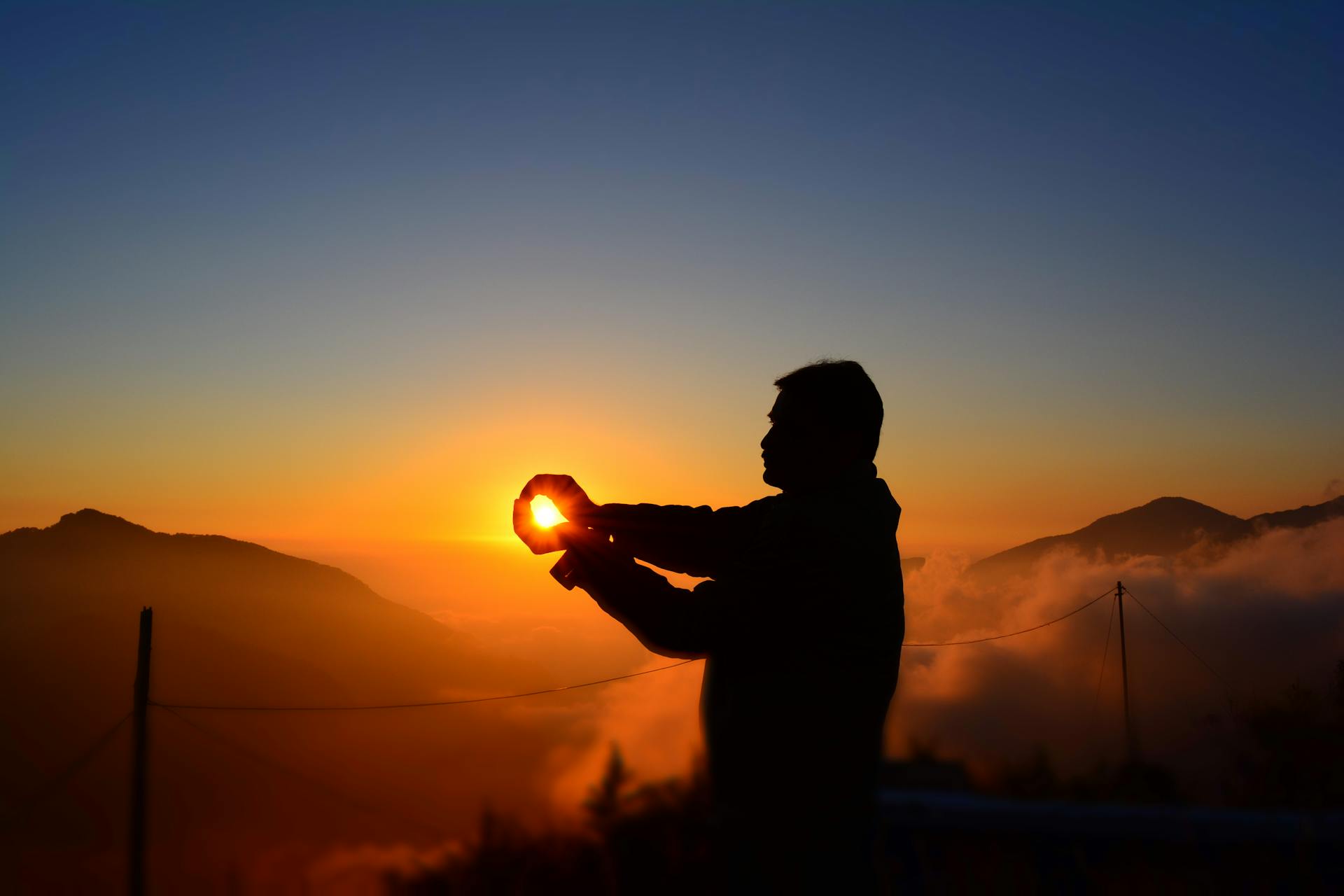 Silhouette of a figure facing a sunrise over distant mountains representing the 1st house of identity and emergence