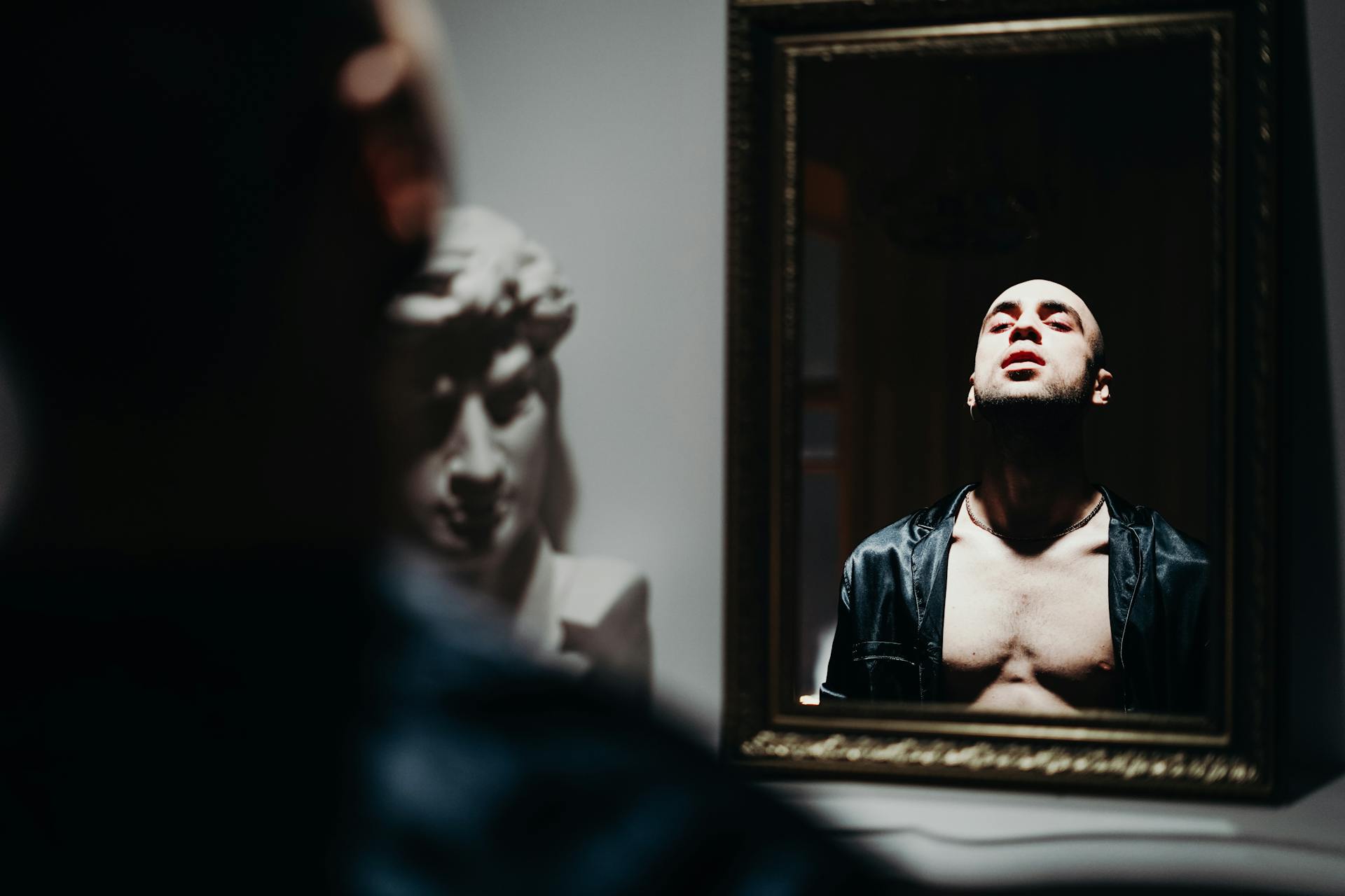 A person facing themselves in a mirror representing the self-image dimension of the 1st house