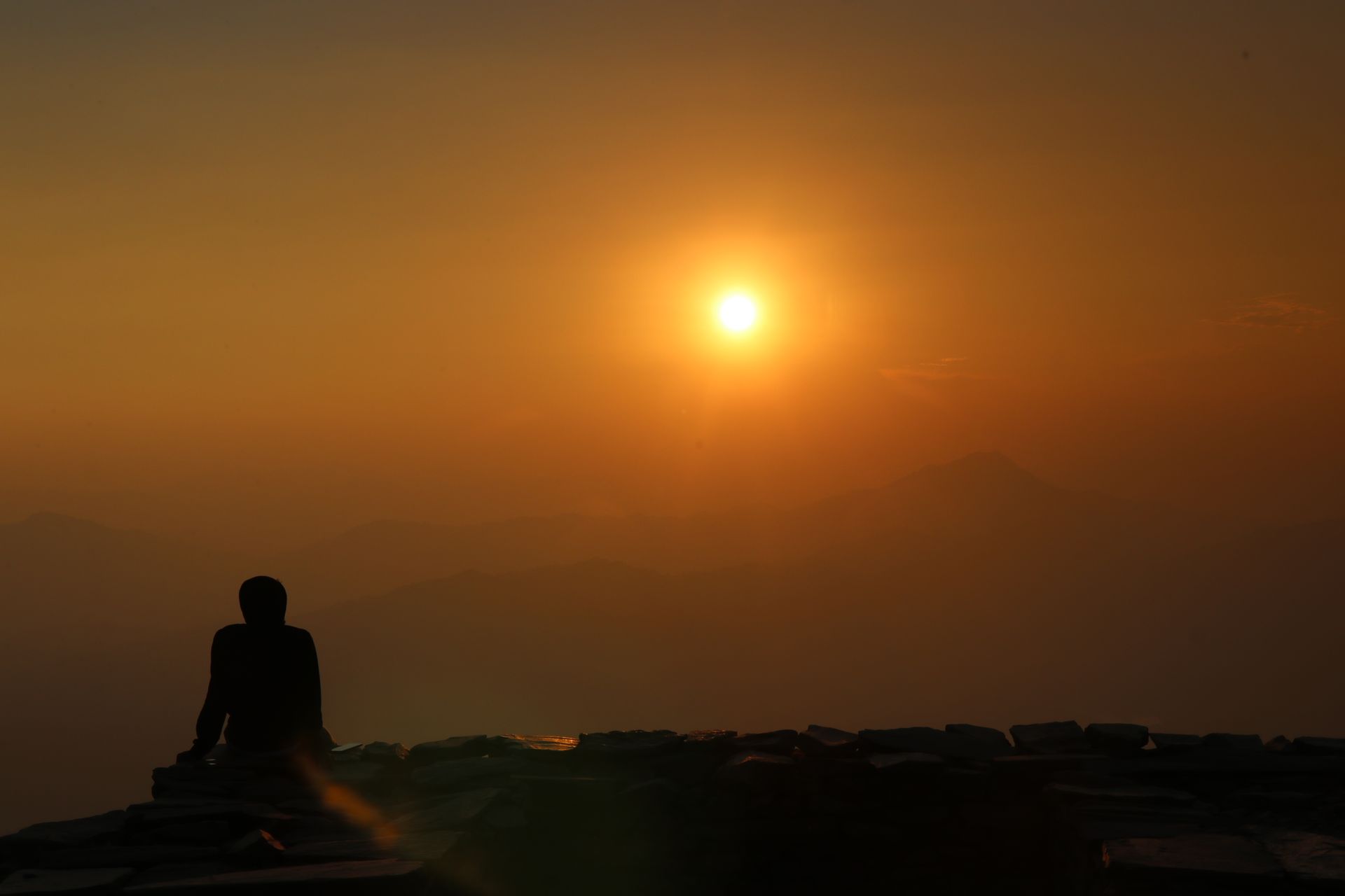 A person sitting in calm meditation at sunrise, representing the focused mindset behind manifestation