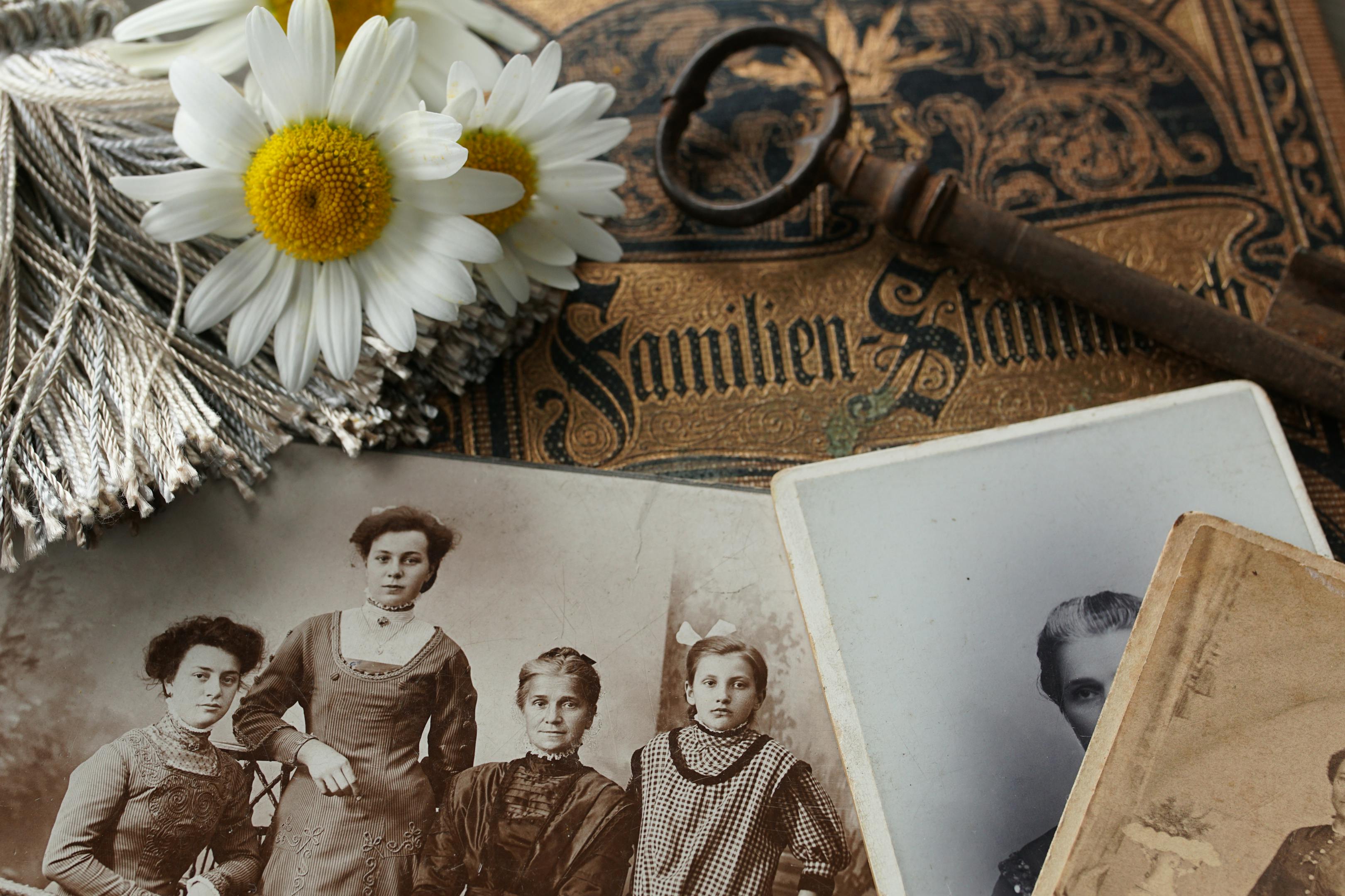 Vintage family photographs and an antique key resting on a wooden surface representing the ancestry themes of the 4th house