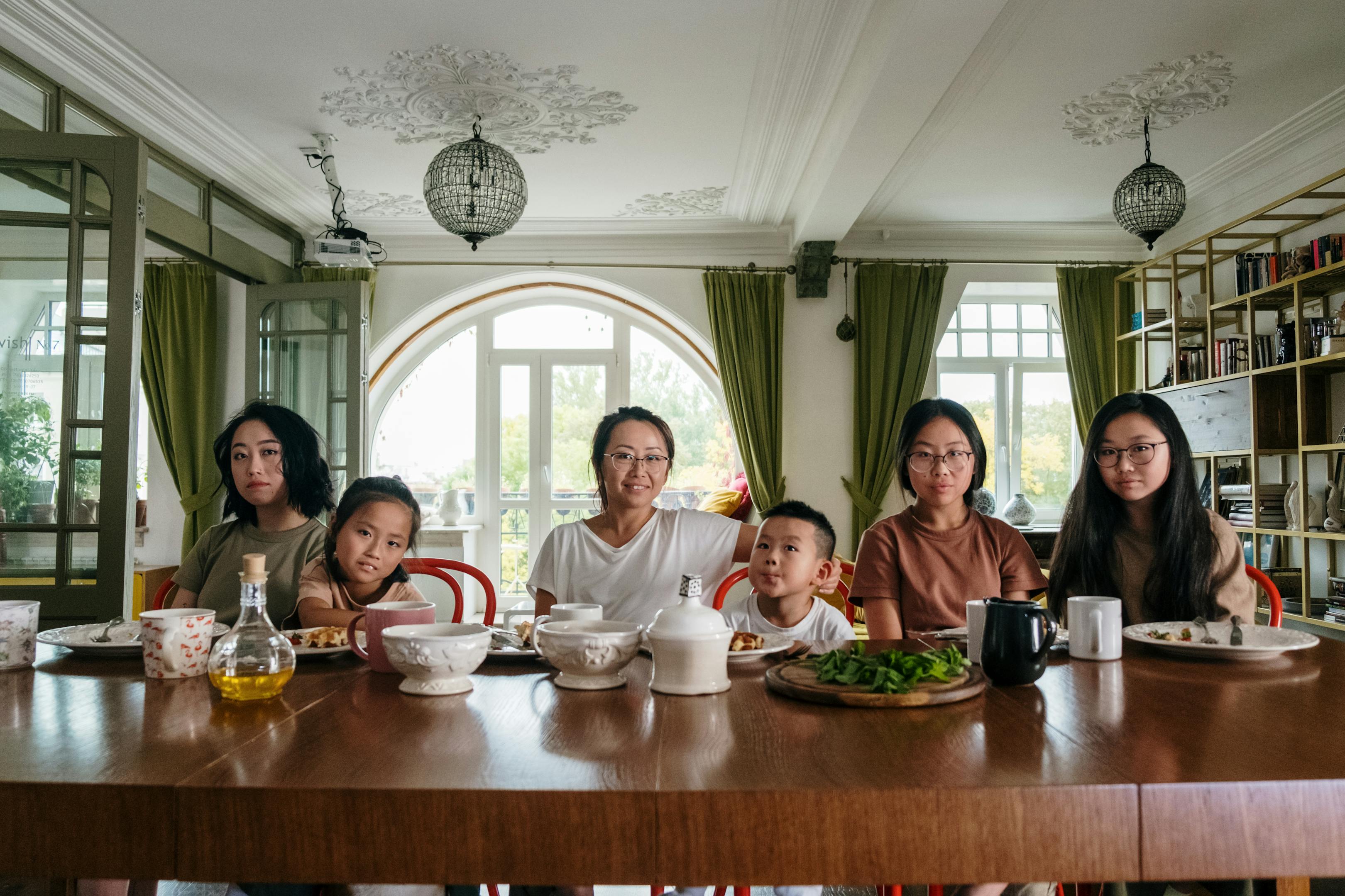 A diverse family gathered around a dinner table in a warmly lit living room representing the home and belonging themes of the 4th house