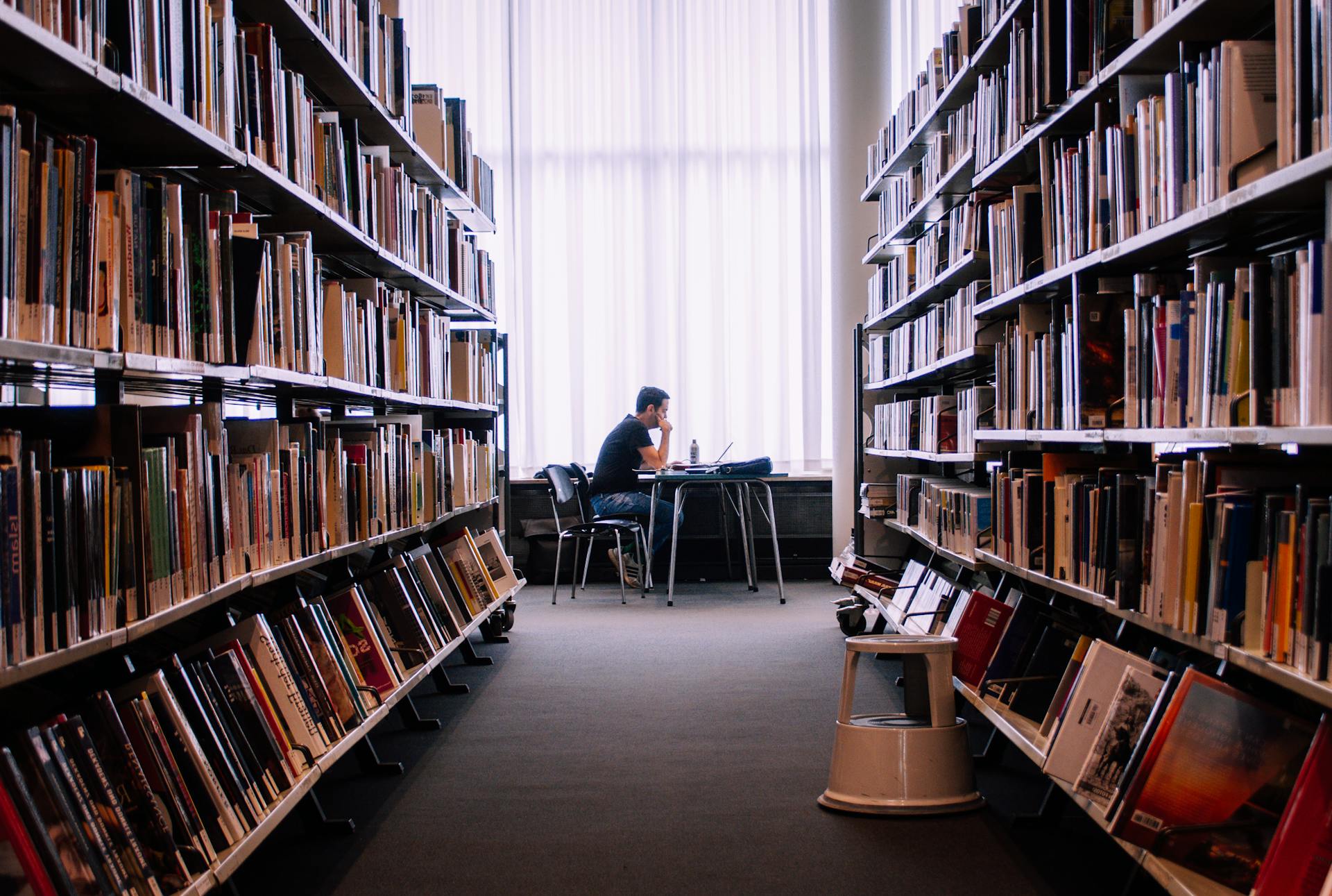 Person reading and studying in a quiet library representing the higher learning of the 9th house