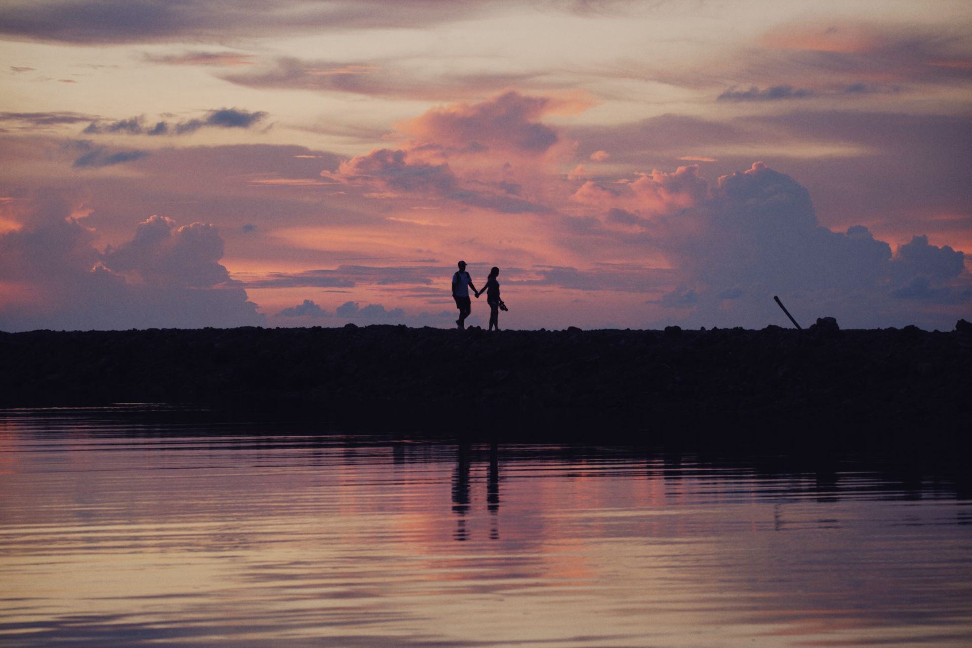 A couple holding hands in silhouette at sunset, representing the new beginnings angel number 1010 brings to love