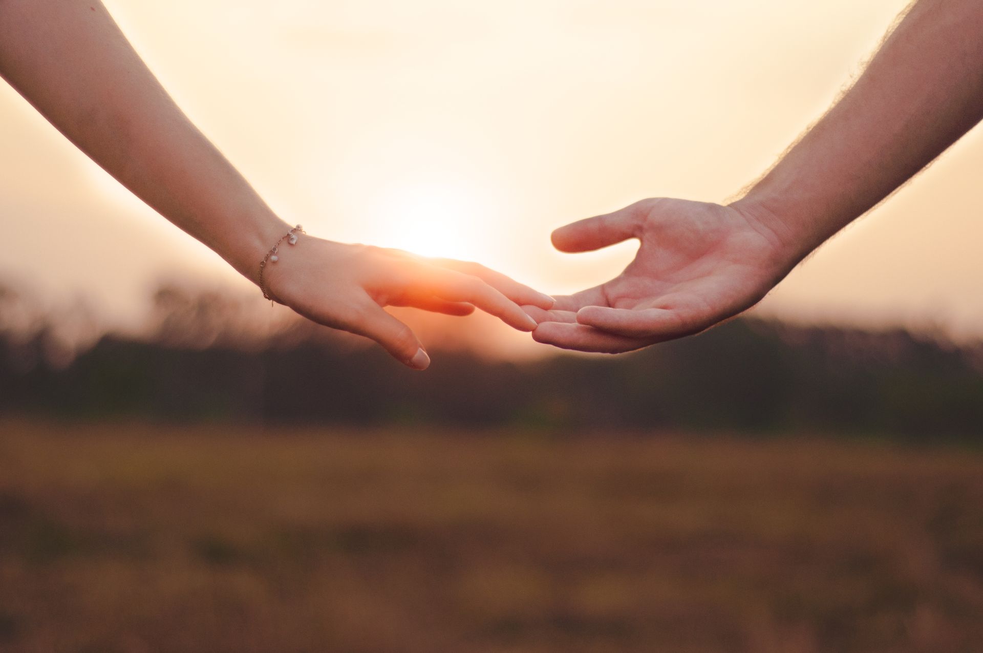 Two people holding hands at sunset, representing partnership, harmony, and the love meaning of angel number 222