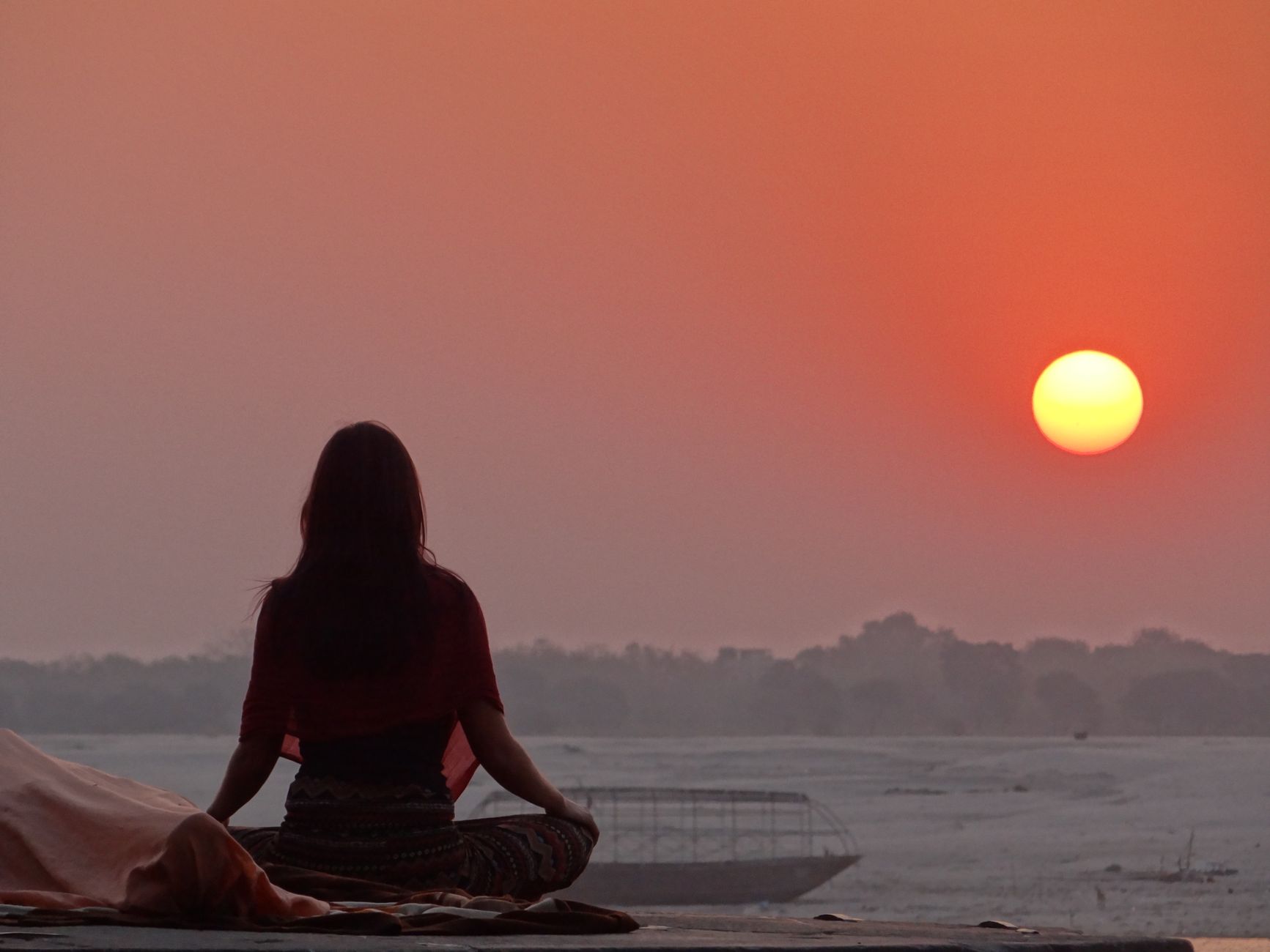 A person meditating at sunrise in a calm natural setting, representing the spiritual support and mind-body-spirit balance of angel number 333