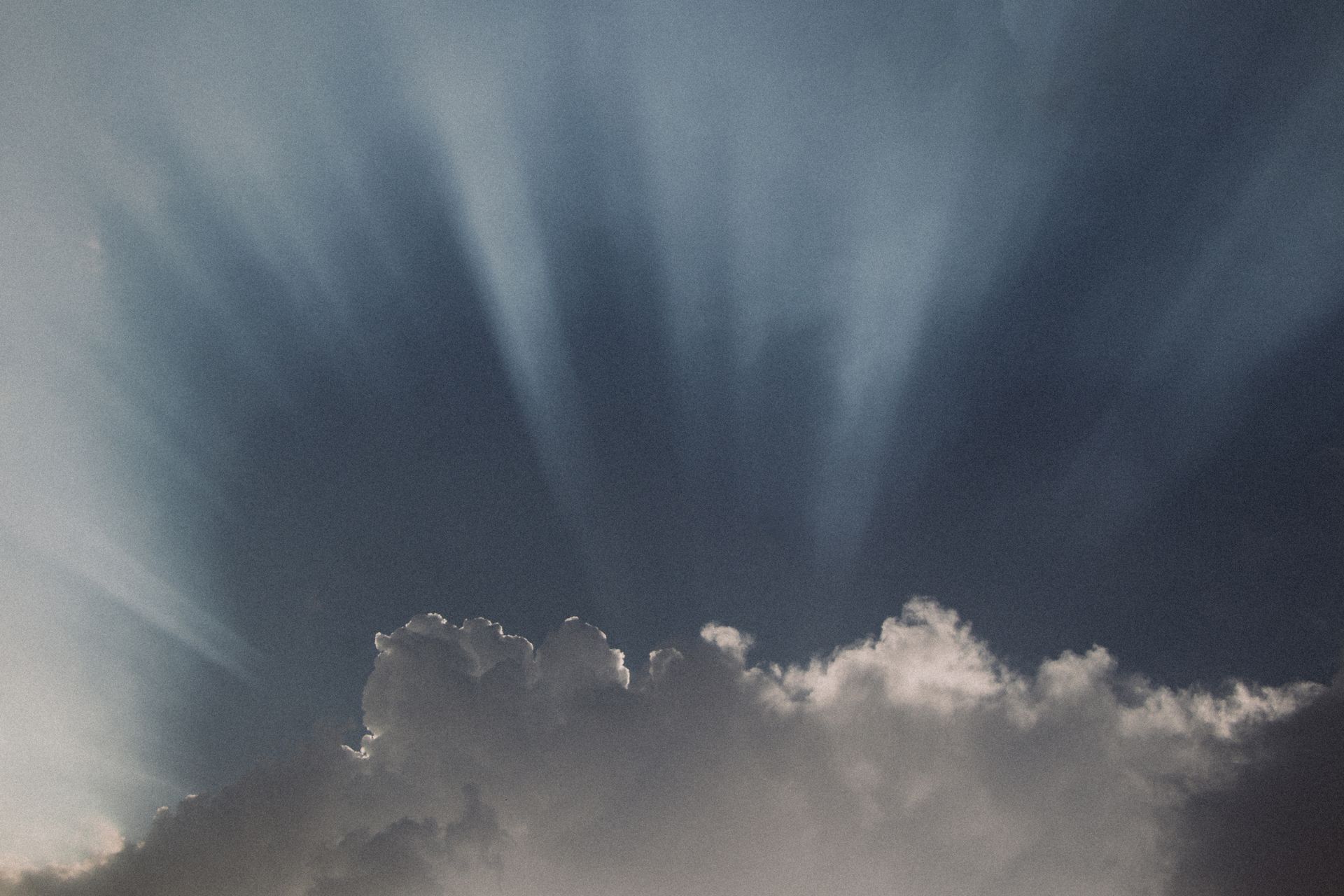Dramatic sunbeams breaking through clouds over an open landscape, representing the freedom and forward motion of the number 5 in numerology