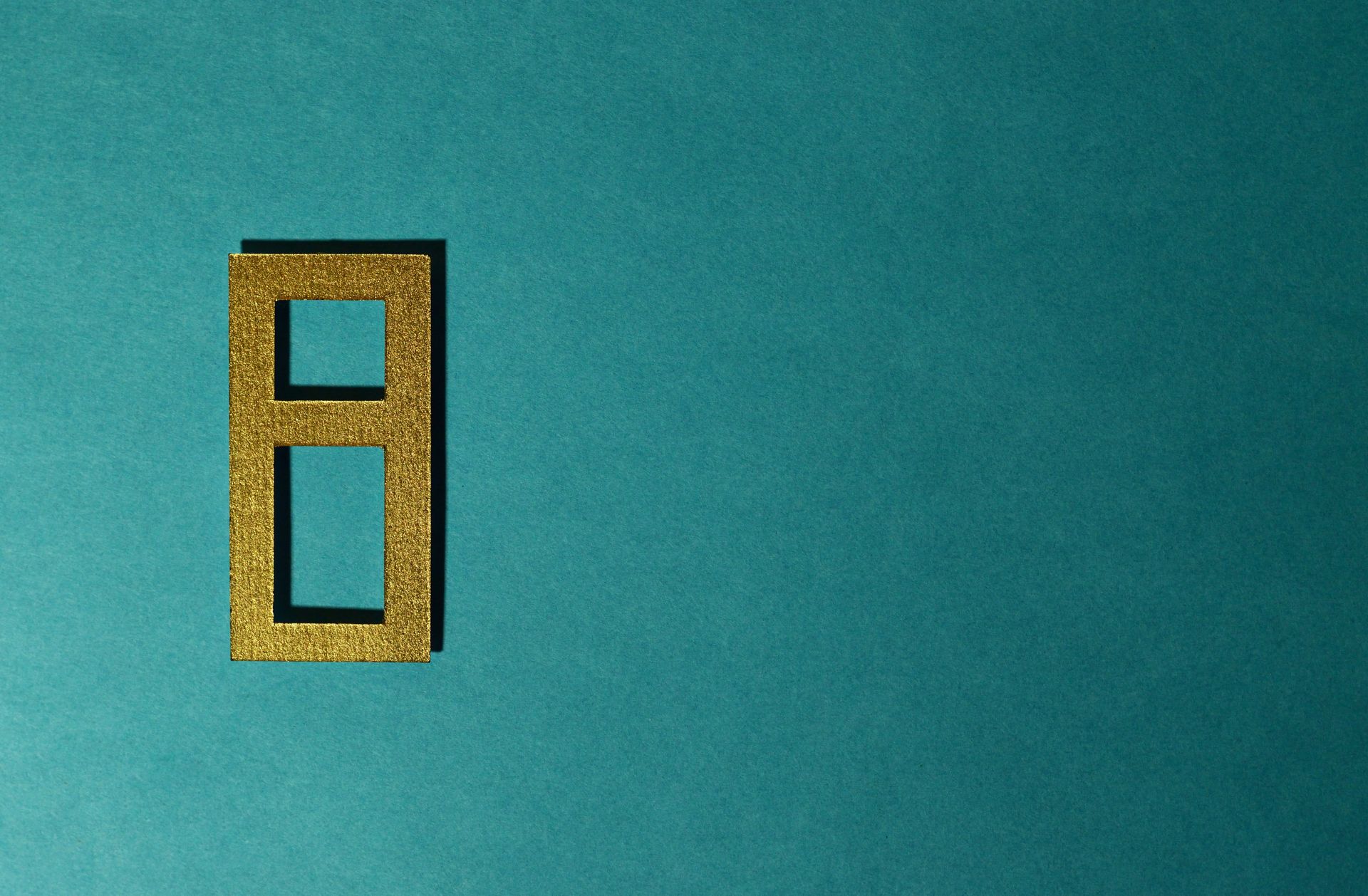 A golden number cutout on a clean teal background, illustrating the numerology behind angel number 666