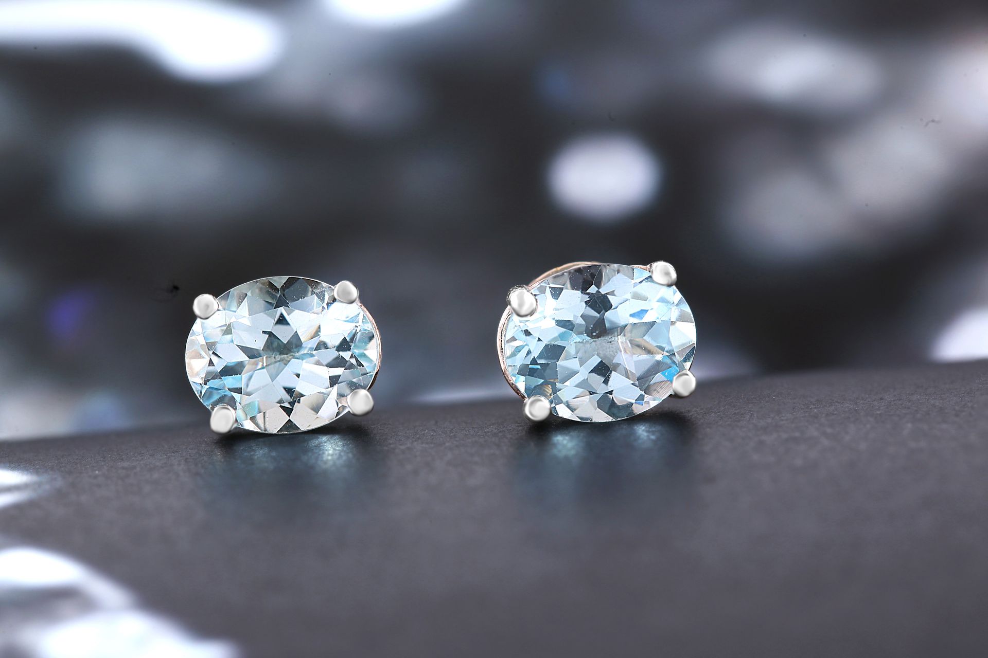 Two pale sky-blue faceted aquamarine gemstone stud earrings, showing the sea-blue color behind aquamarine meaning