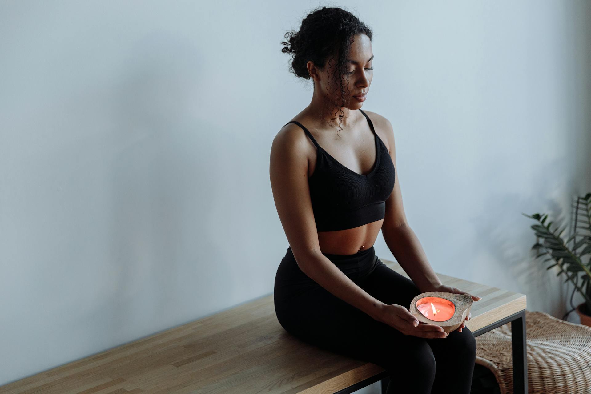 A woman meditating peacefully with a lit candle representing mindful self-care practices aligned with astrological energy
