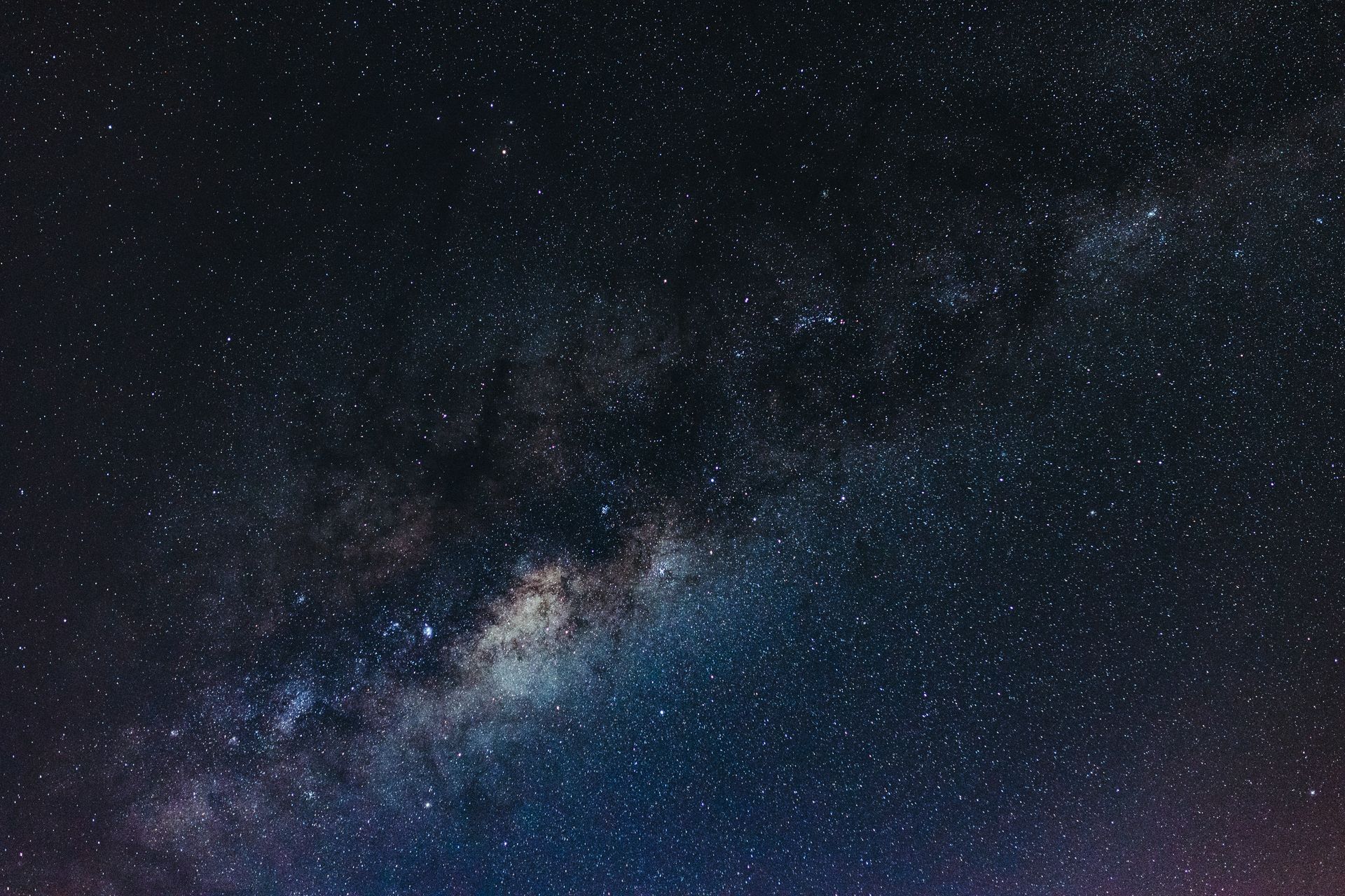A sweeping Milky Way arching over a dark, star-filled horizon