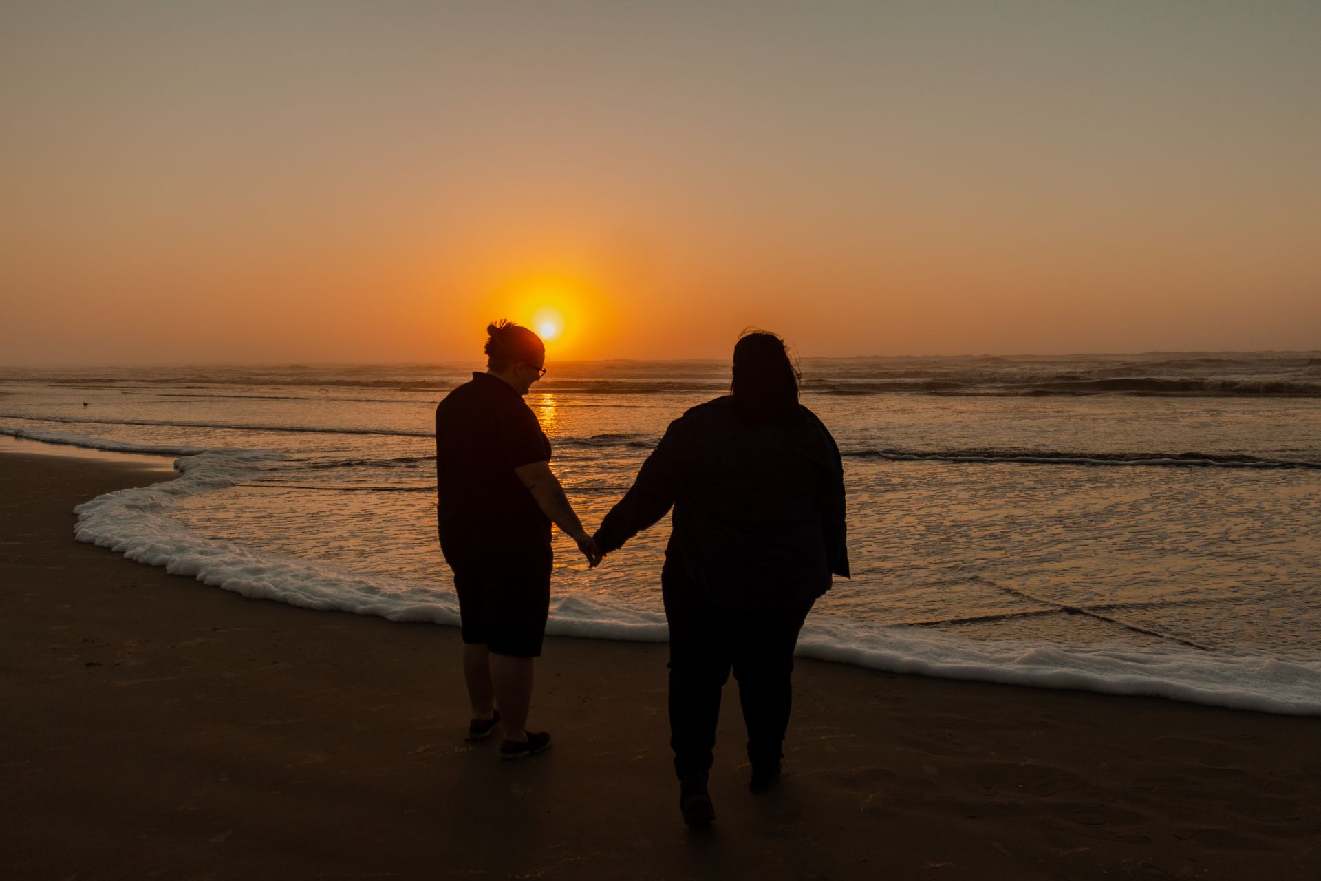 A couple holding hands at sunset, representing the steady security that earth and fire signs seek in love