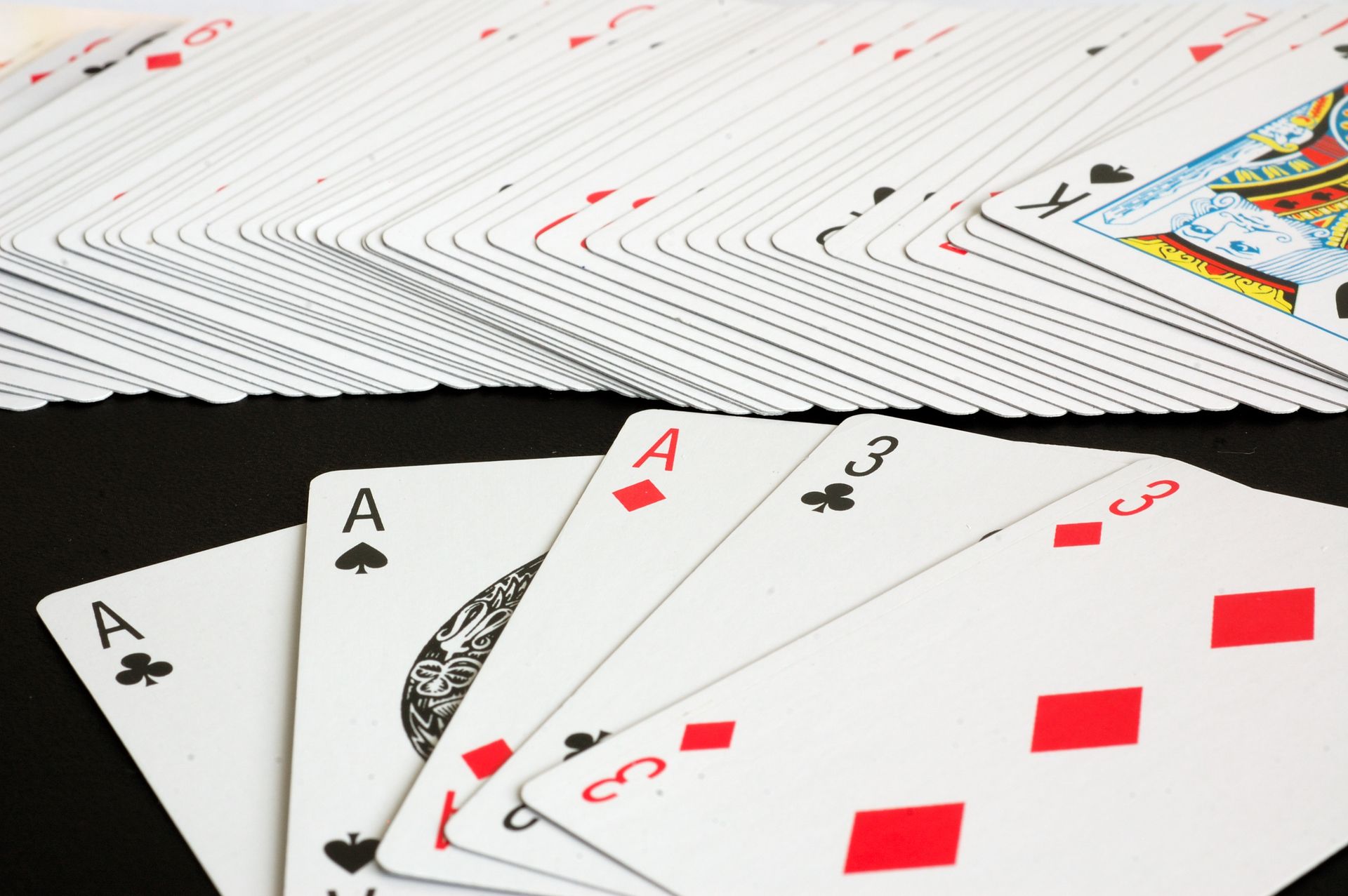 A fanned deck of ordinary playing cards on a black surface with aces and number cards face up, representing cartomancy divination