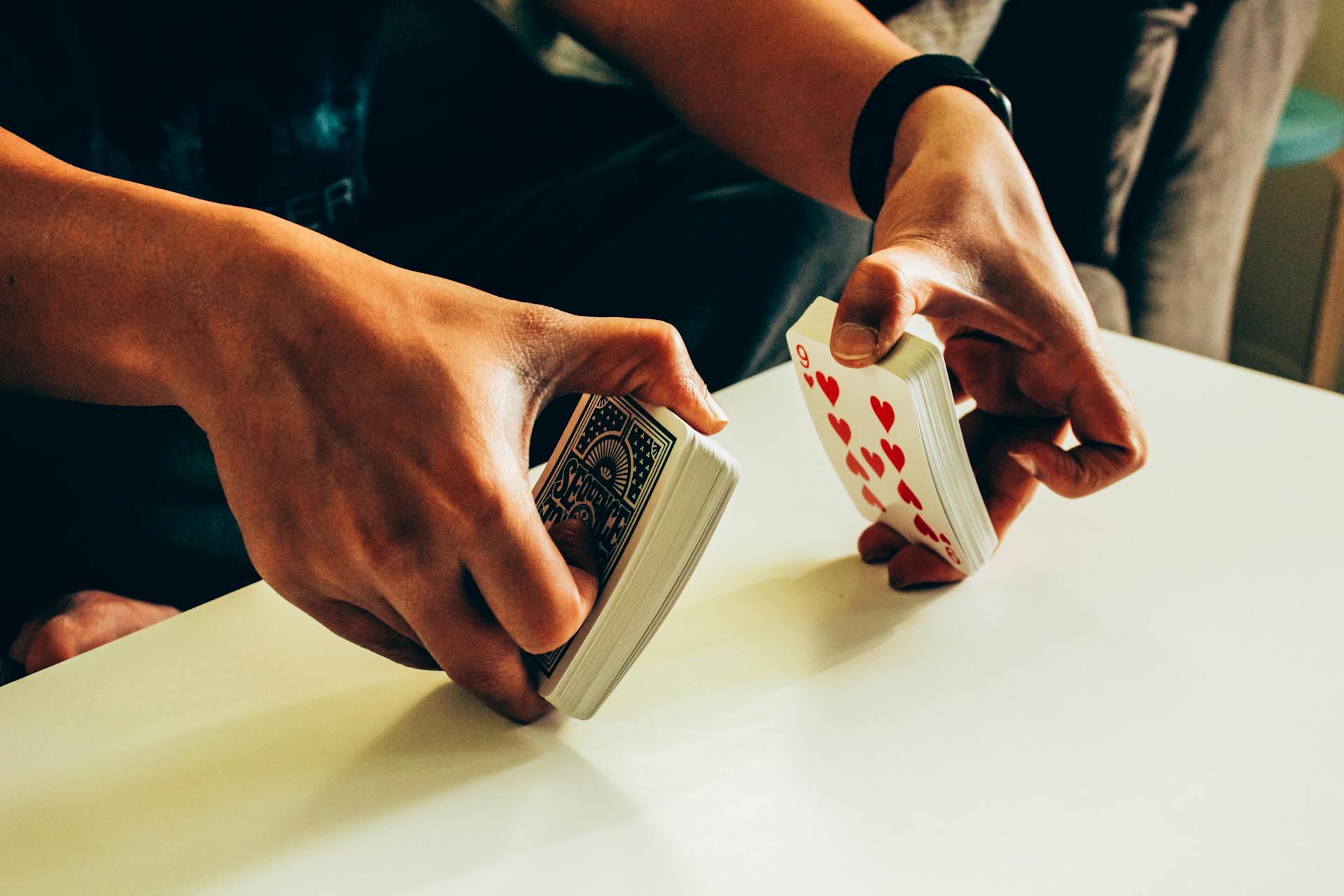 Hands shuffling a deck of ordinary playing cards before laying out a cartomancy spread