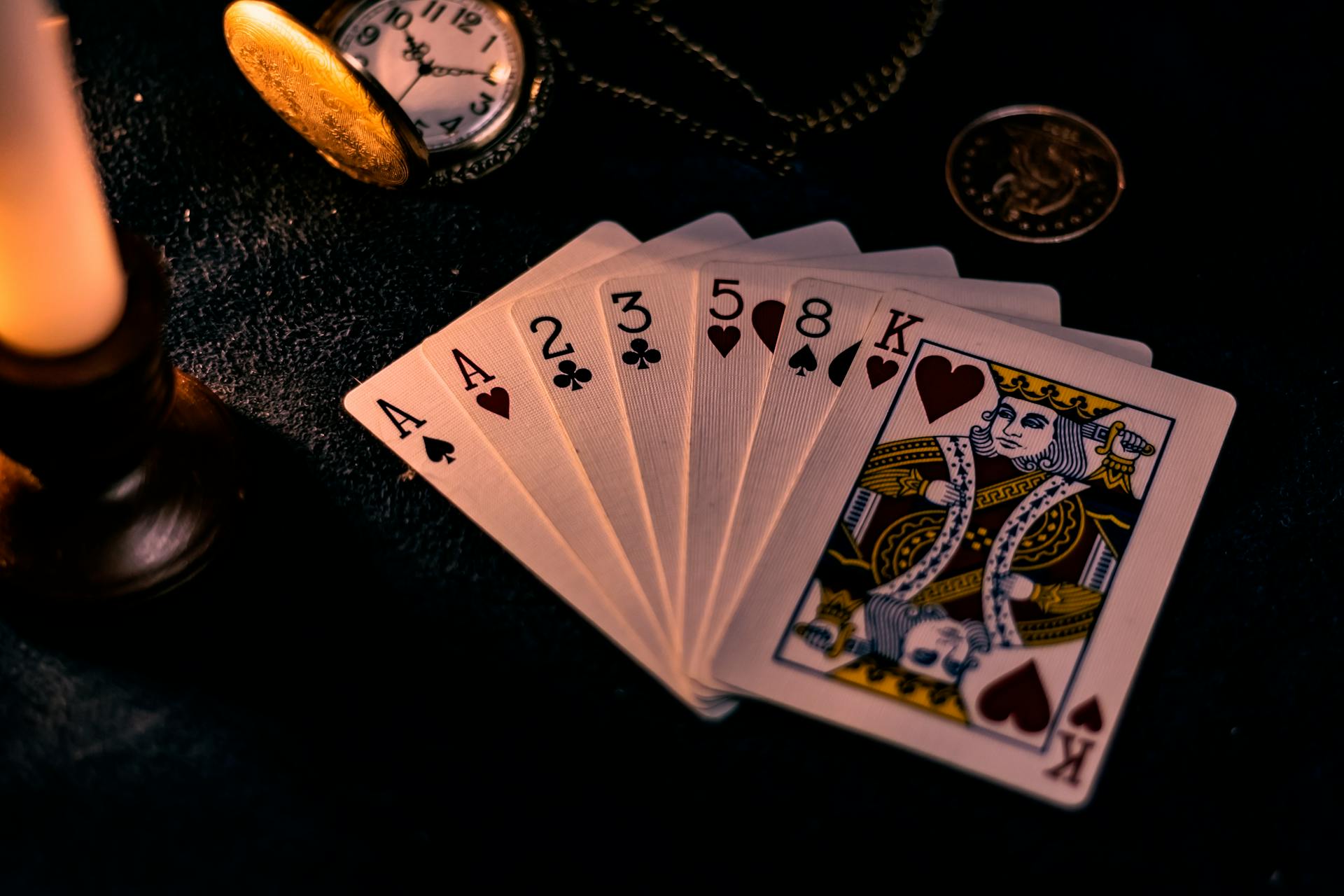 Vintage playing cards spread across a dark surface, suits and numbers visible for a cartomancy reading