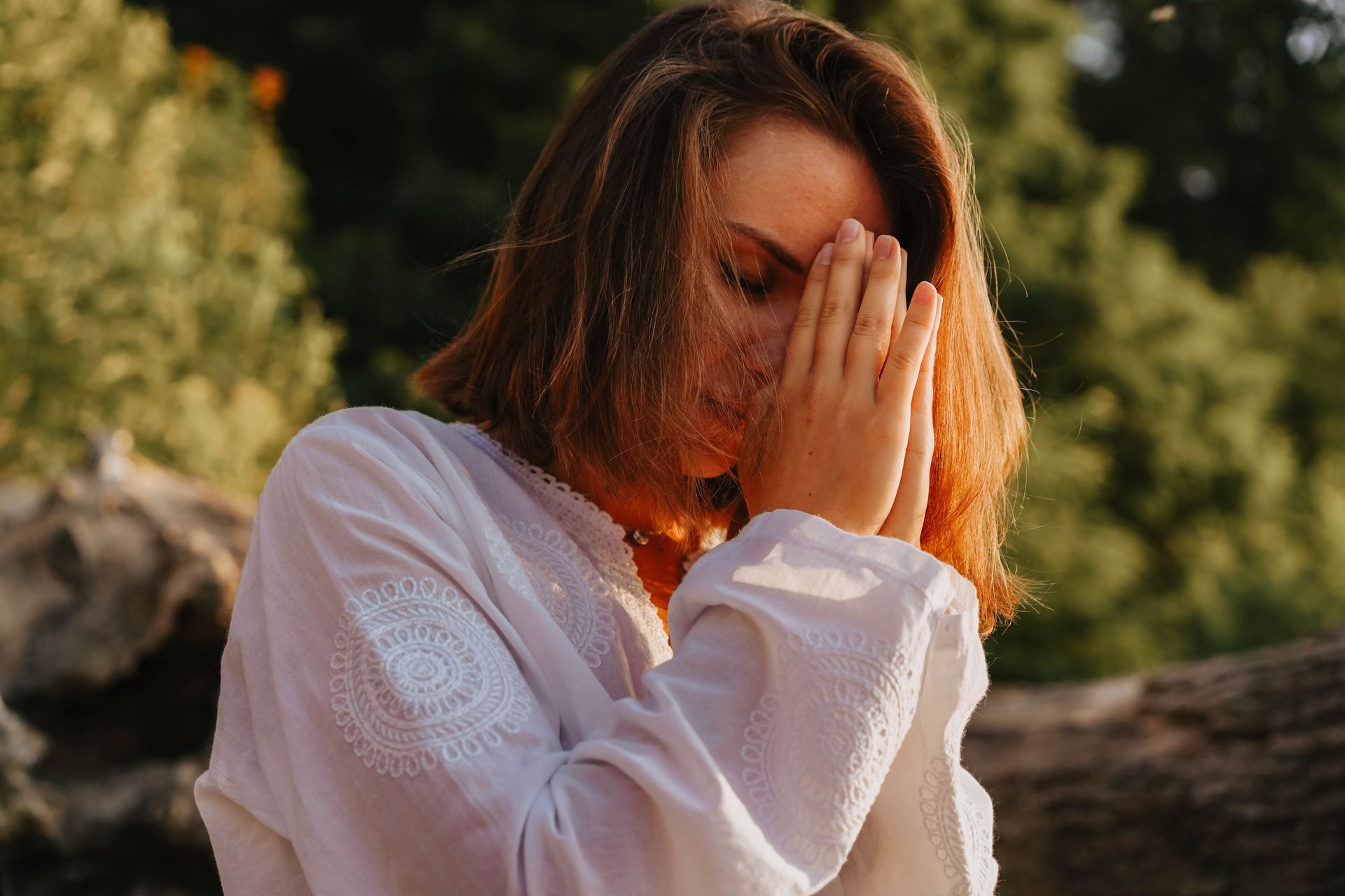 A woman meditating outdoors with her eyes closed in a peaceful pose, tuning in to intuition