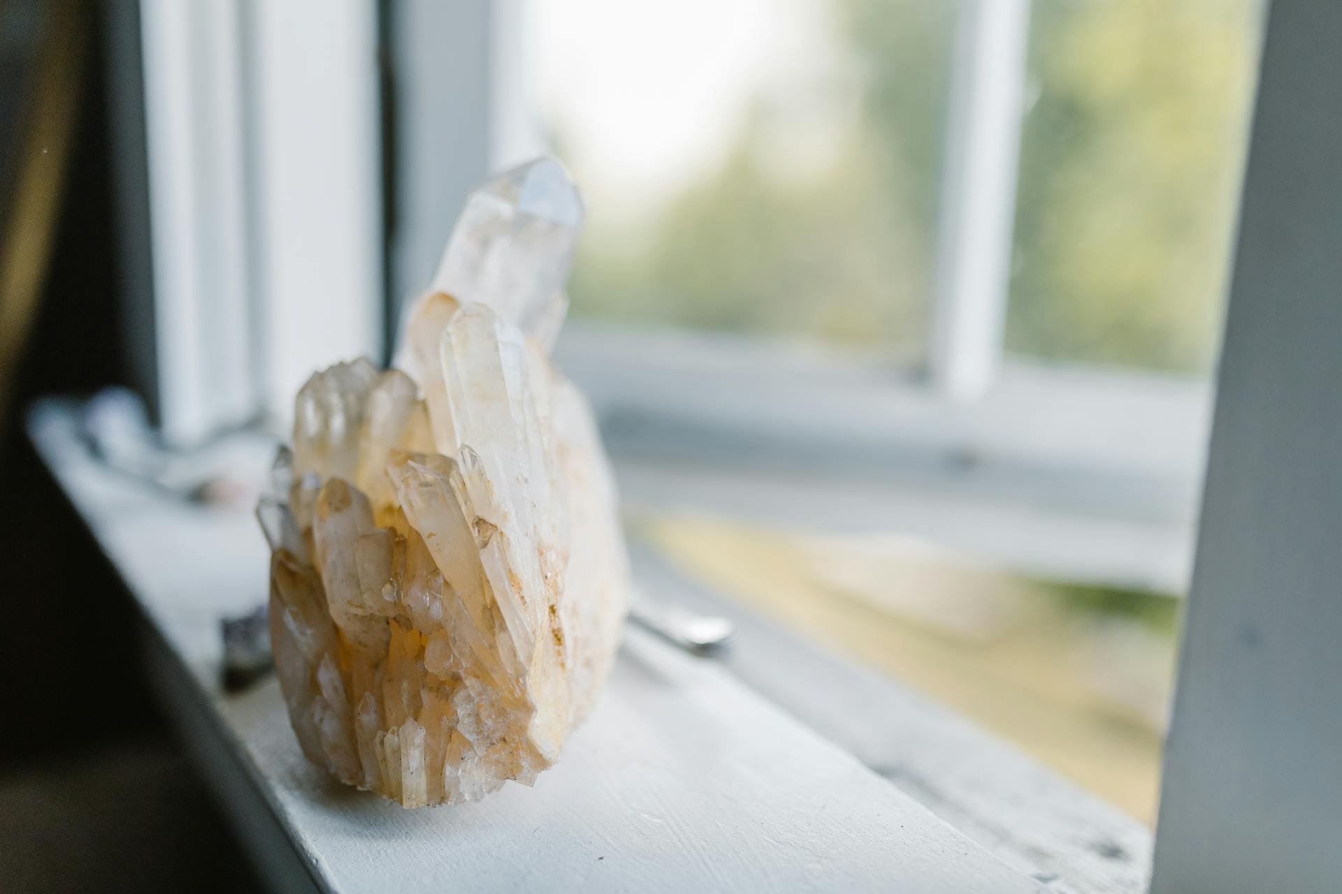 Close-up of a natural quartz crystal cluster on a sunny windowsill evoking tranquility and cleansing energy