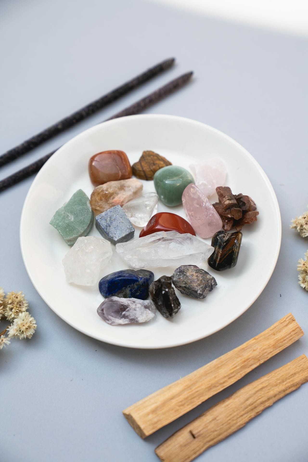 A collection of colorful healing crystals displayed on a white ceramic plate for spiritual practice