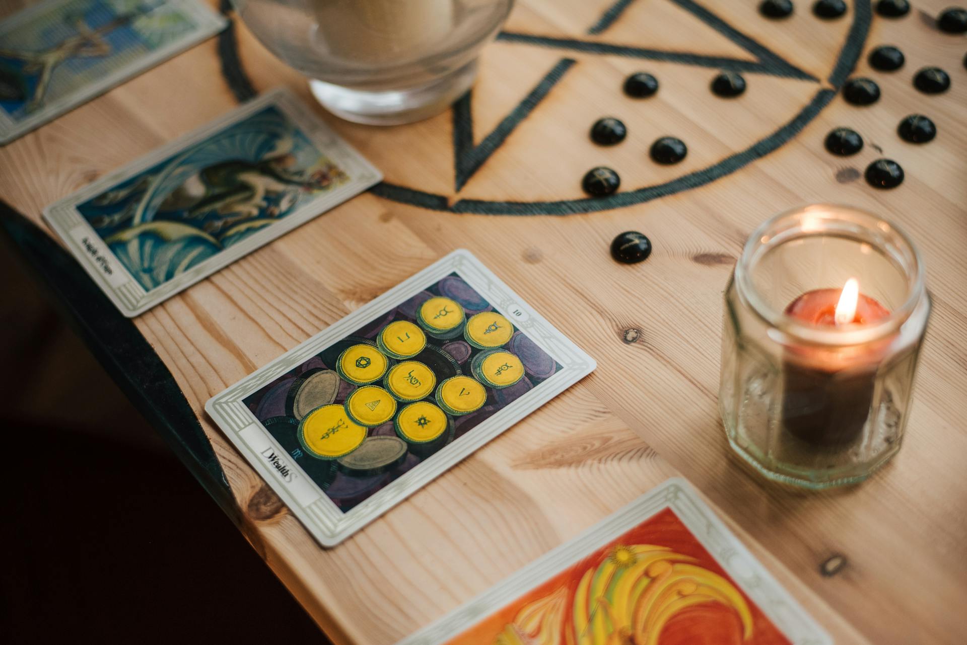 Tarot cards and a glowing candle on a wooden table creating an intimate space for daily card study and reflection