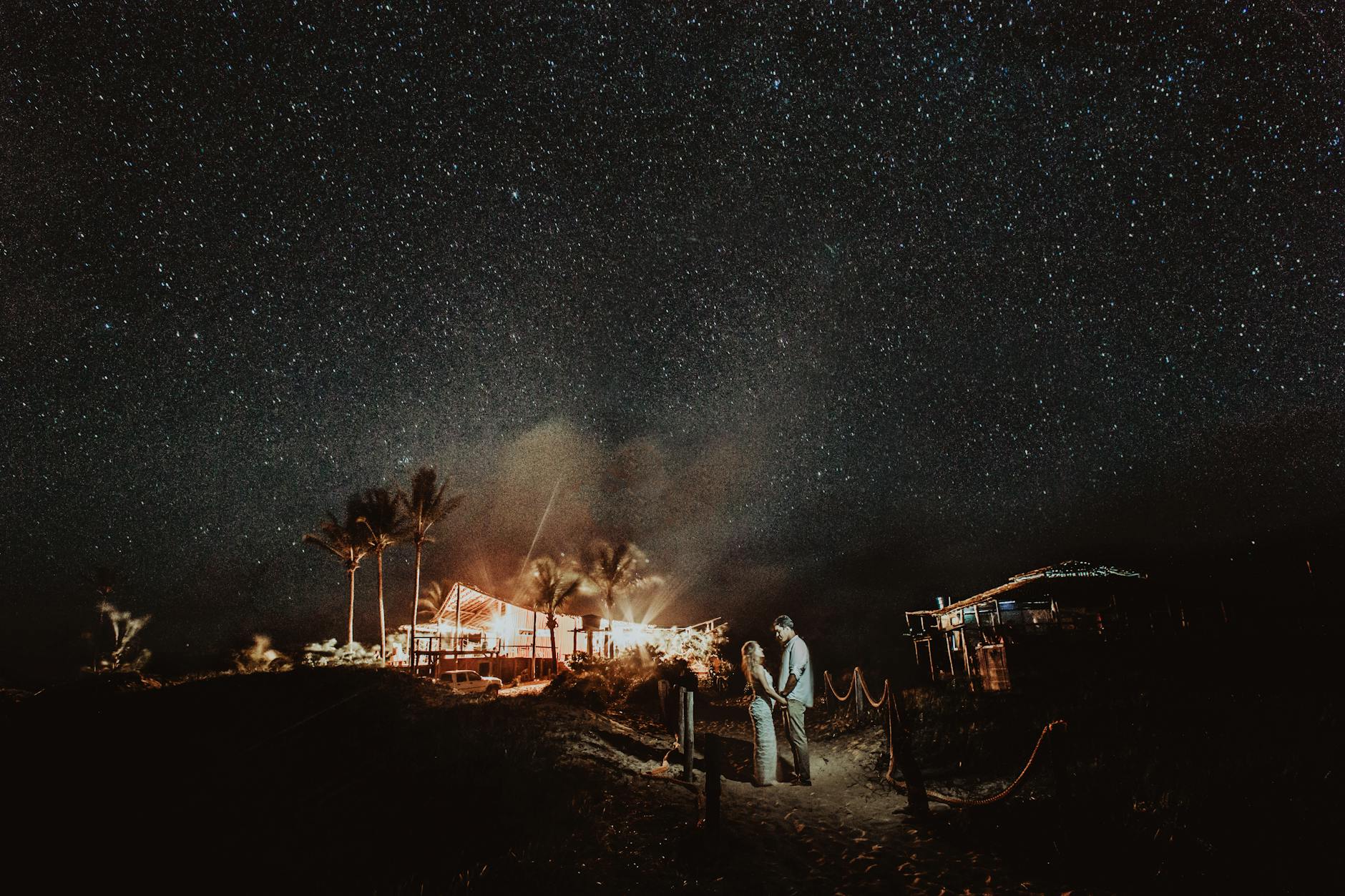 Two silhouettes under a starry night sky representing the midpoint moment of a relationship in time and space