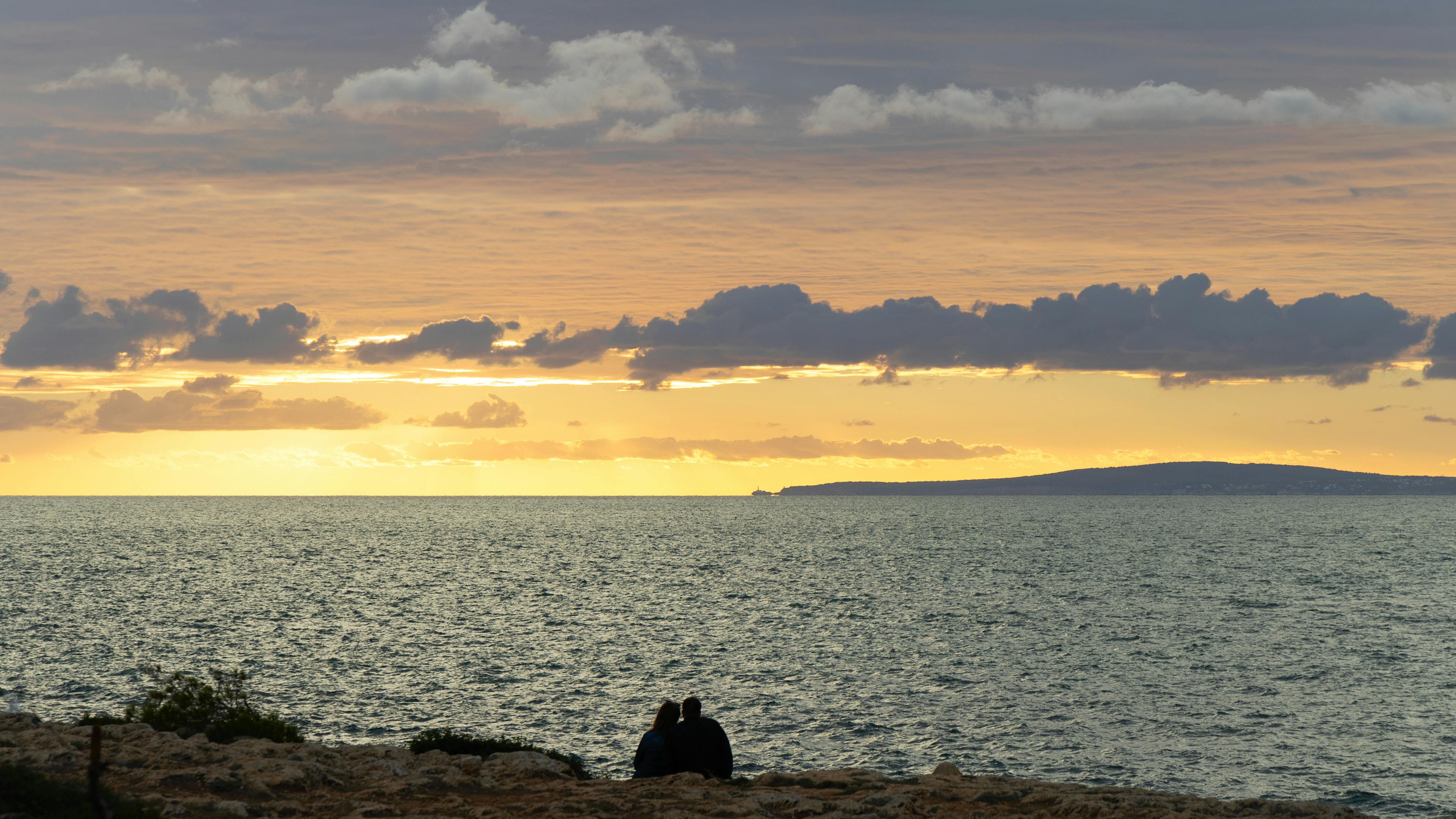 Couple silhouetted against a sunset horizon representing the astrological partnership axis