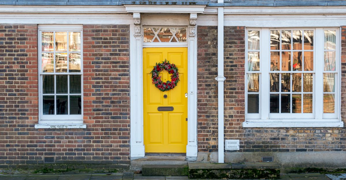 A hand mounting brass numerals on a front door, illustrating how to find your house number in numerology