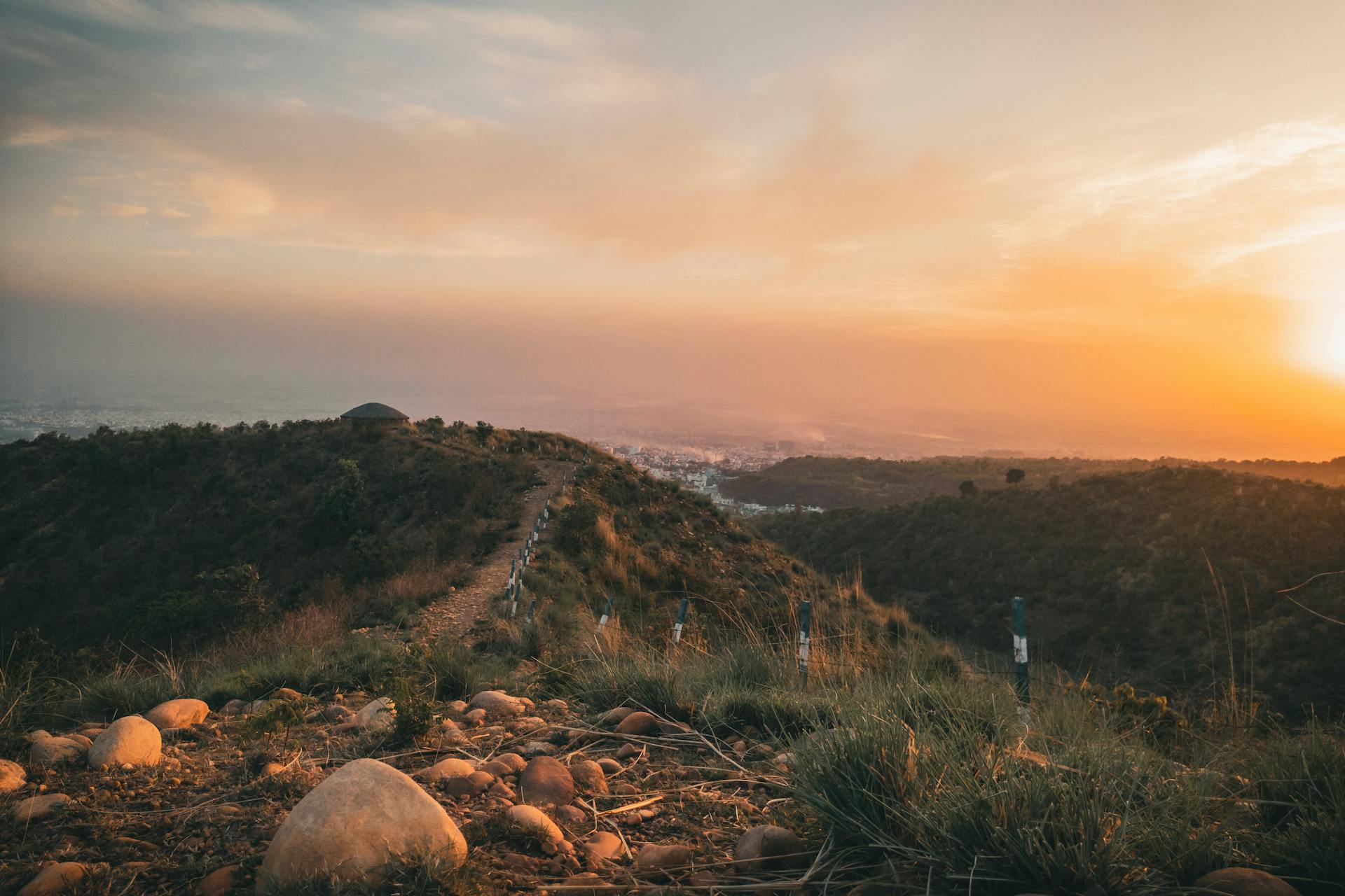 Tranquil rural landscape with a path winding through hills during a stunning sunset representing expansion and possibility