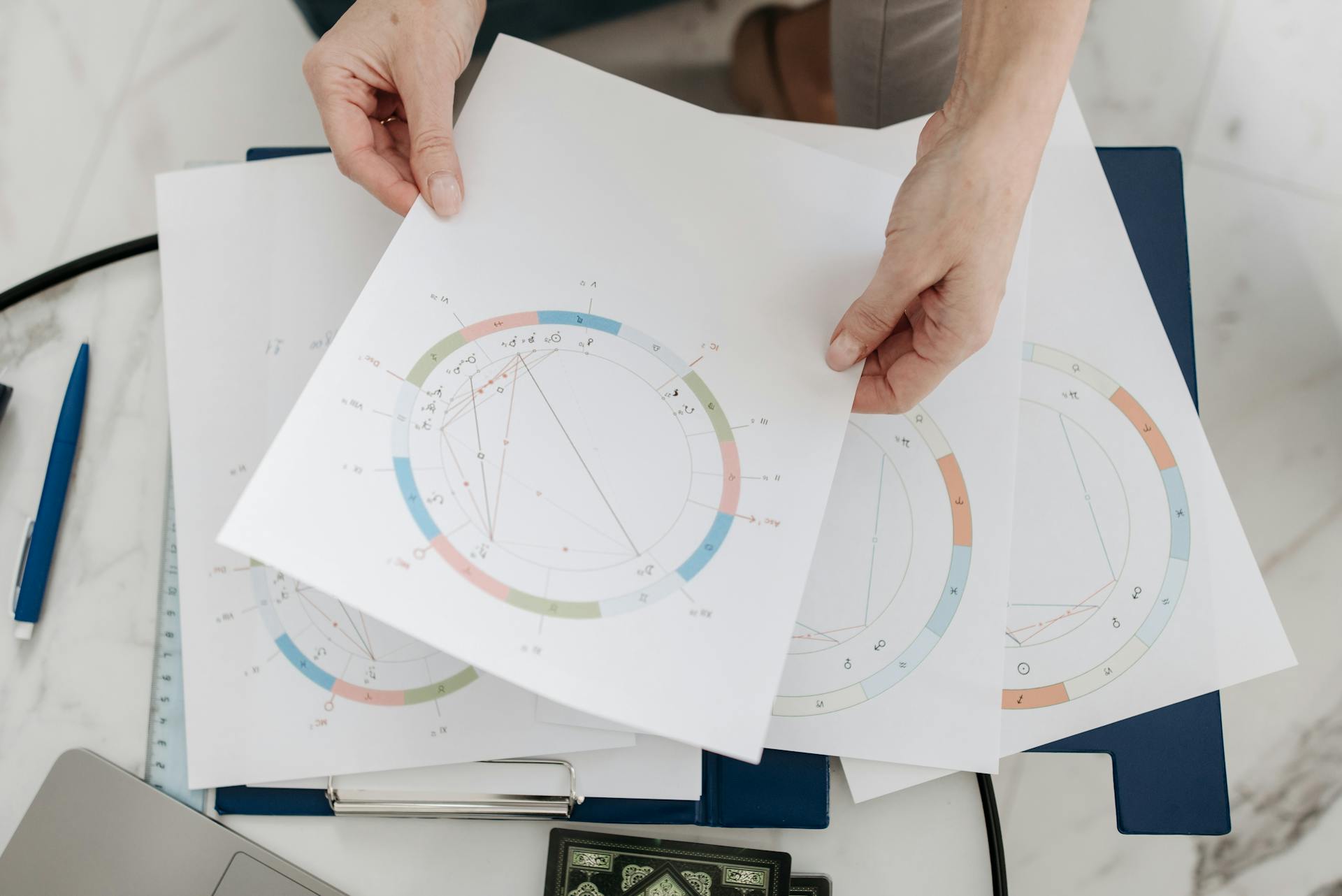 Hands holding astrological charts and graphs symbolizing the study of karmic patterns in the natal chart