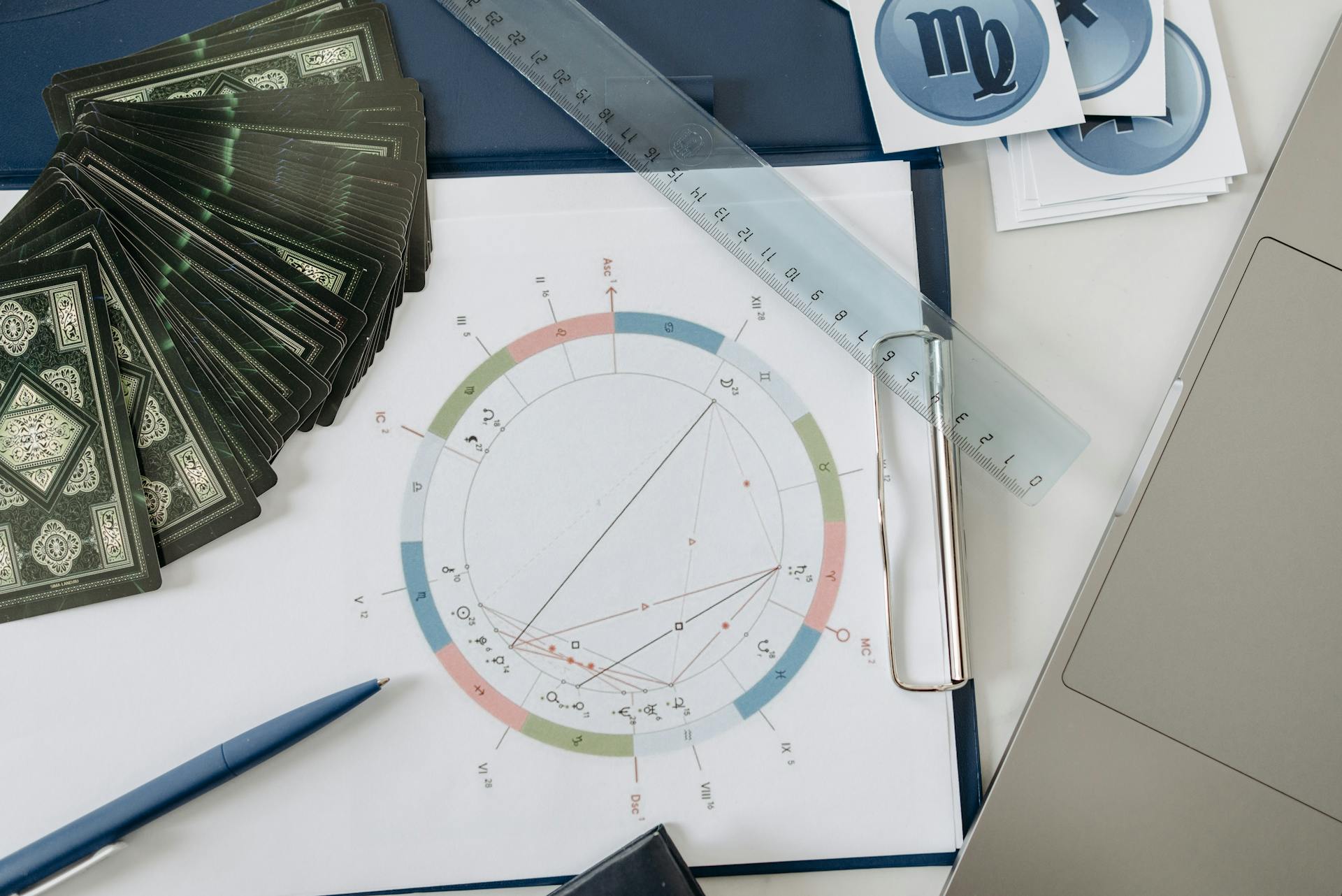 Flat lay of astrology tools including tarot cards and a natal chart on a wooden desk for karmic chart analysis