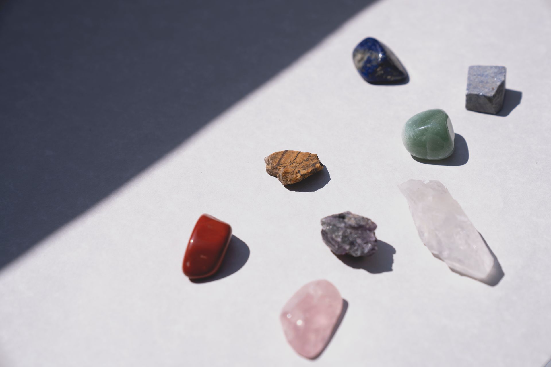 A collection of healing crystals on a light surface, representing how to use and identify real lapis lazuli