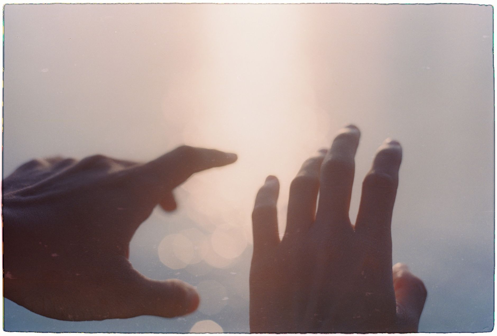 Open hands reaching toward warm sunlight in an open sky, symbolizing the law of attraction