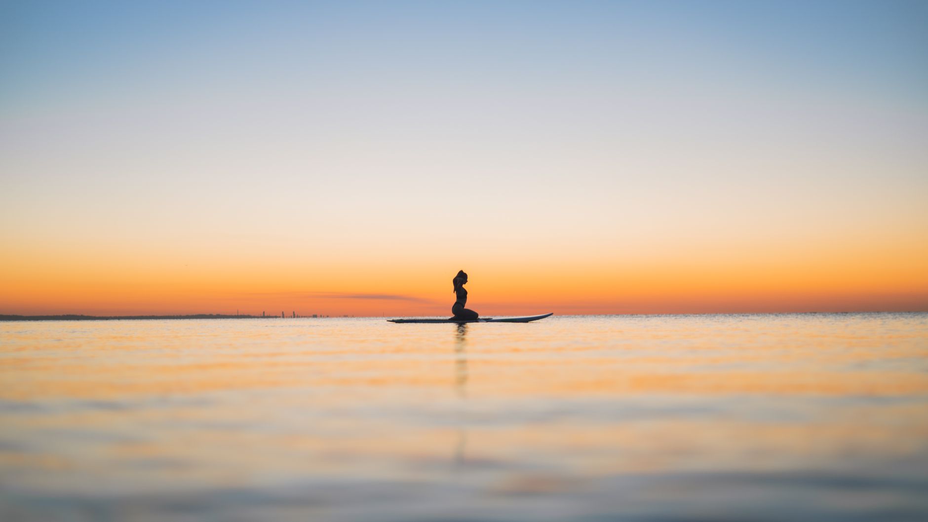 A person meditating peacefully outdoors as the sun rises