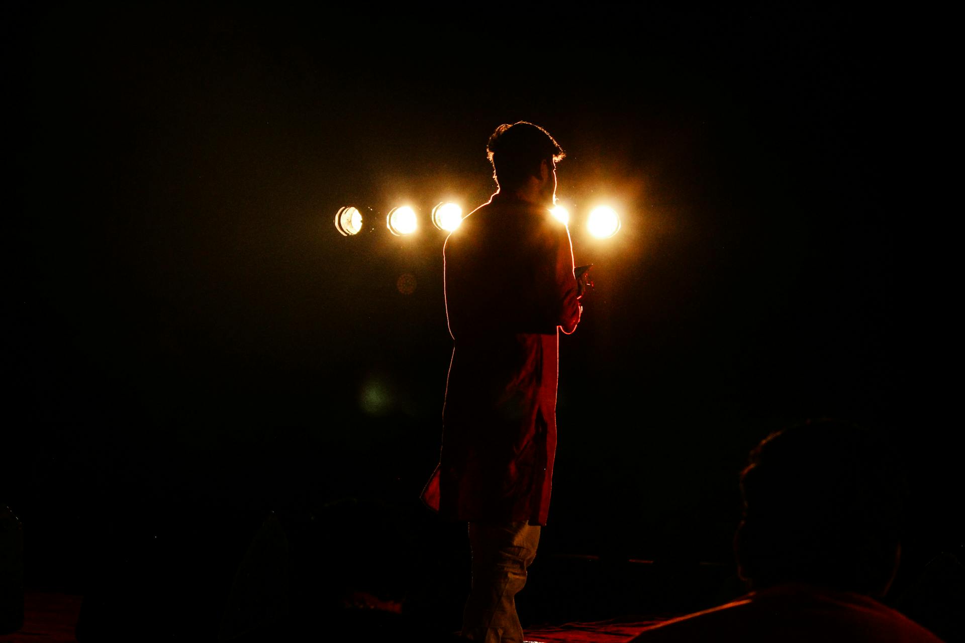A performer stepping into a bright spotlight, representing Leo's natural pull toward center stage and being seen