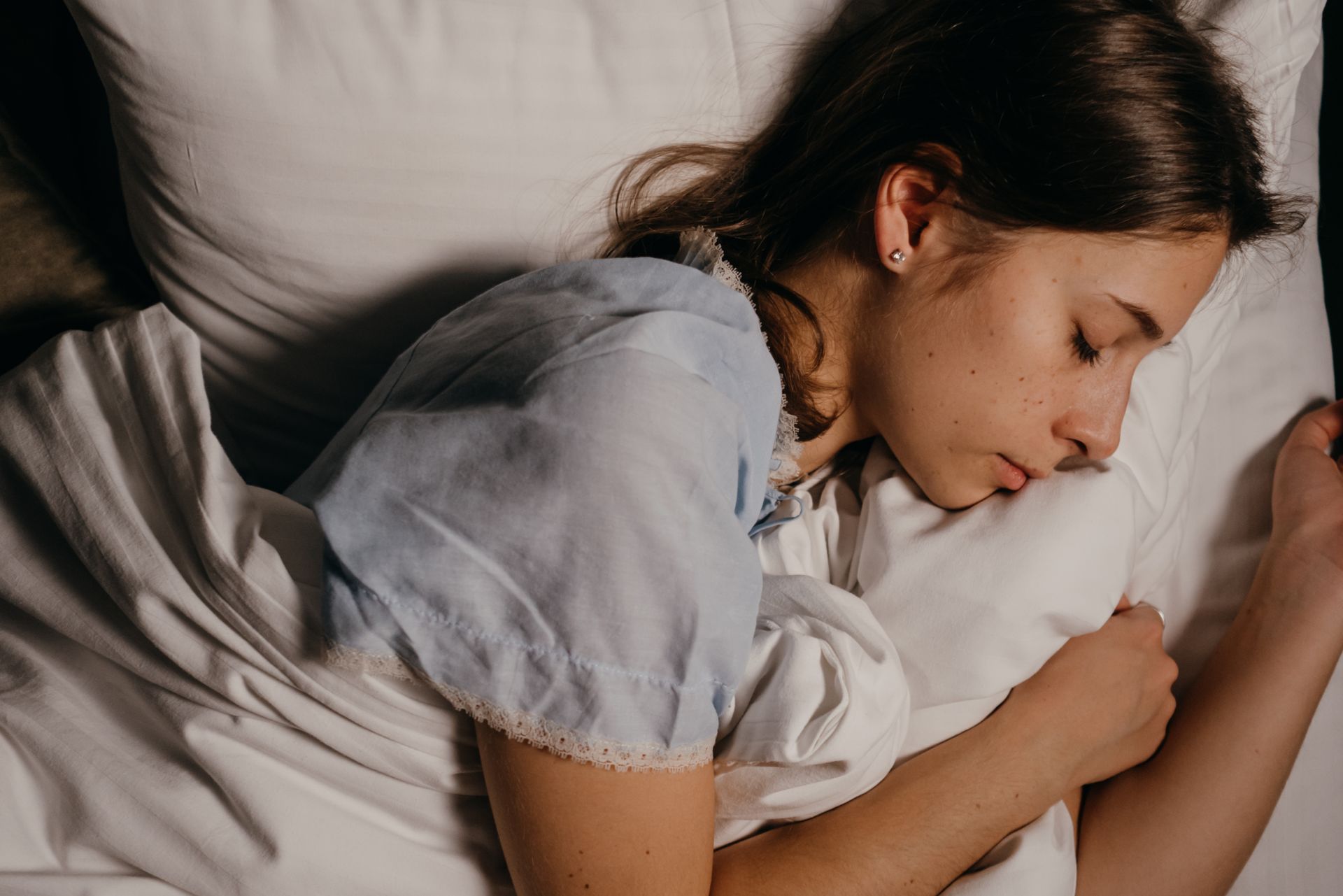 A person asleep in bed at night, illustrating the REM sleep stage where lucid dreams occur