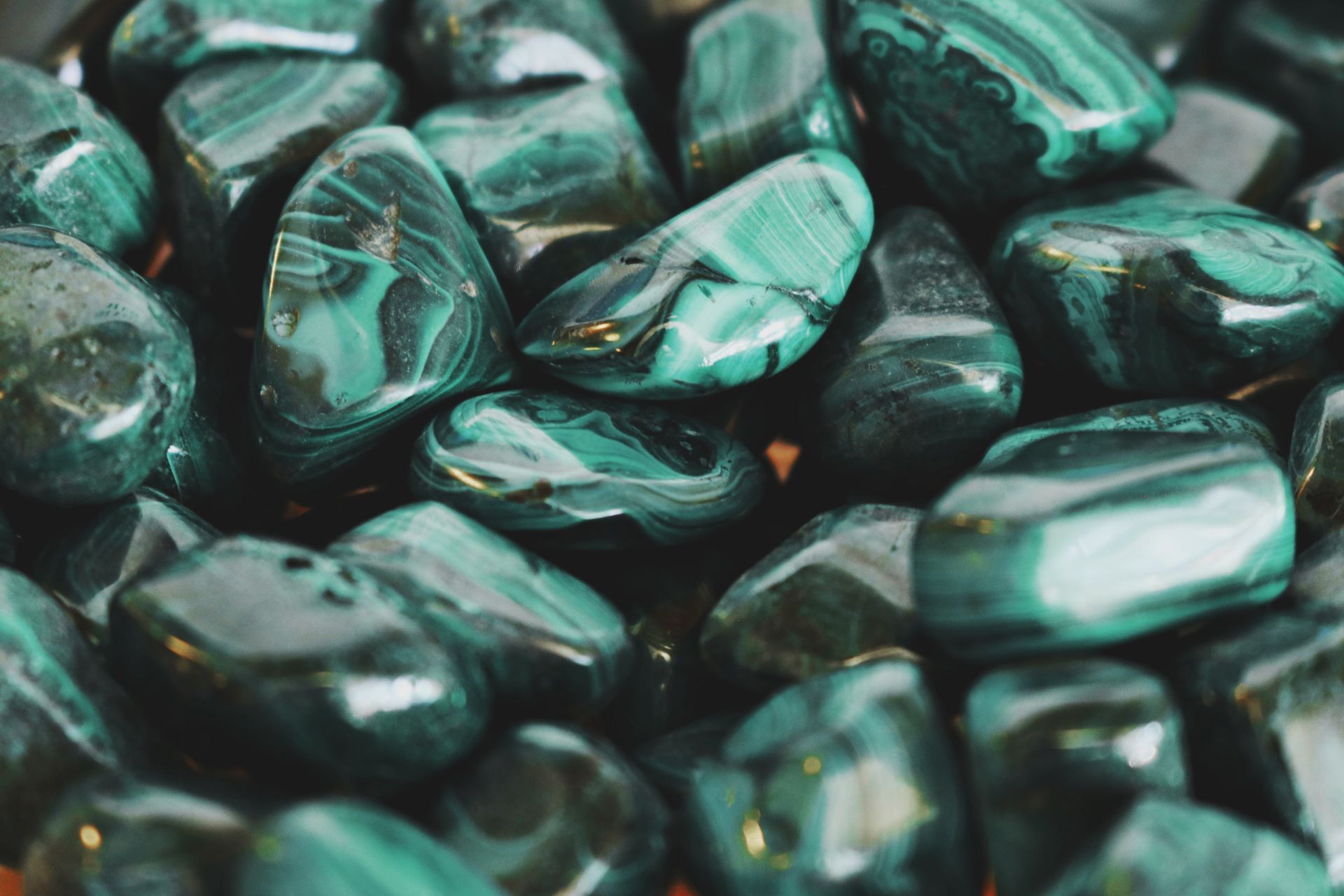 Polished malachite stones showing rich green swirls and banding, representing malachite healing properties and heart chakra work