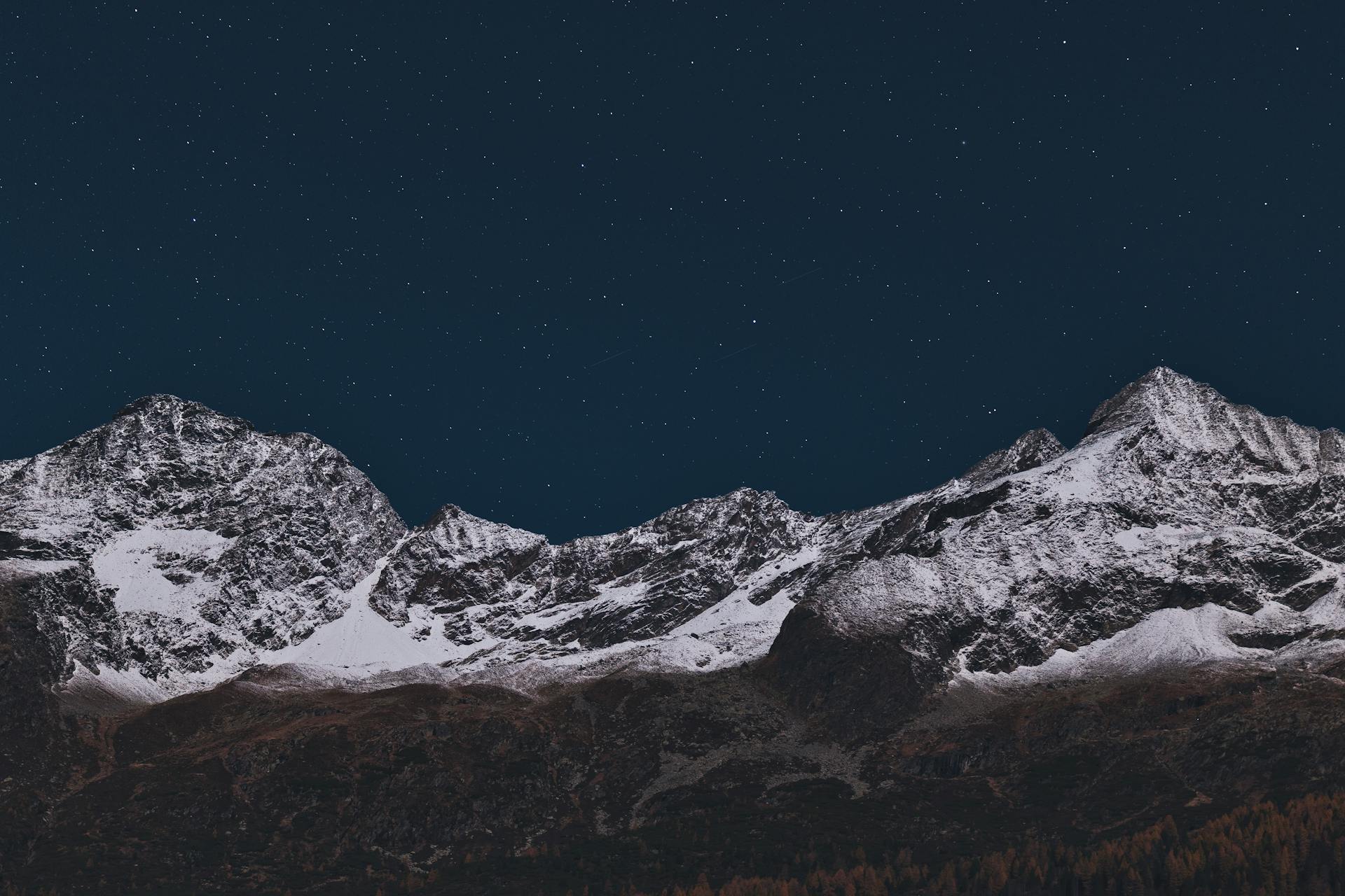 Snow-covered mountains beneath a vast starry sky