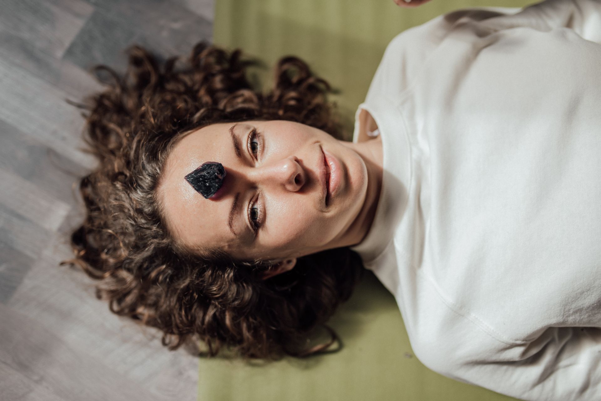 A person resting with a healing crystal on the third eye, representing how moldavite is used in meditation