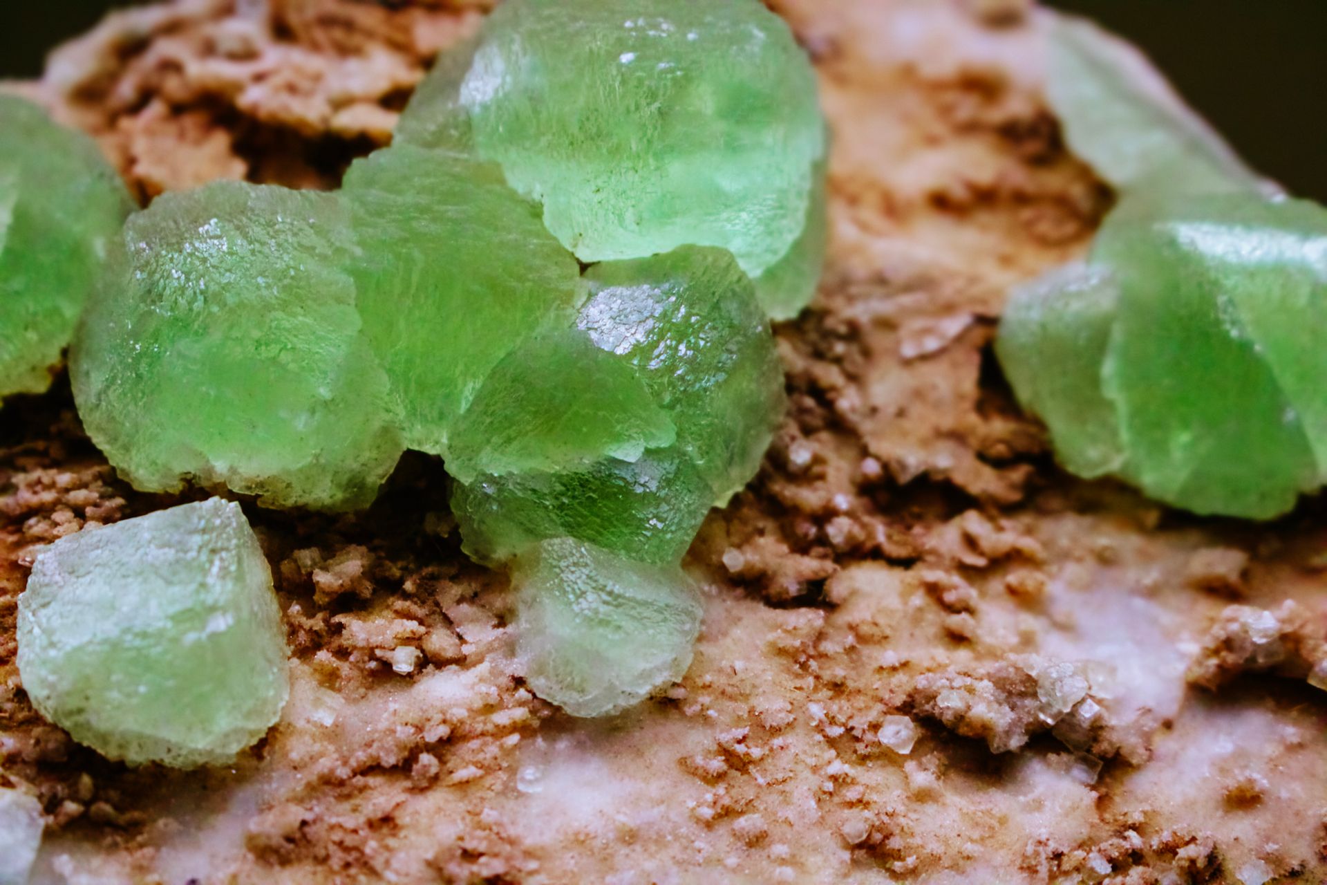 Textured green crystals on a rough mineral surface, representing moldavite meaning and its transformative healing properties