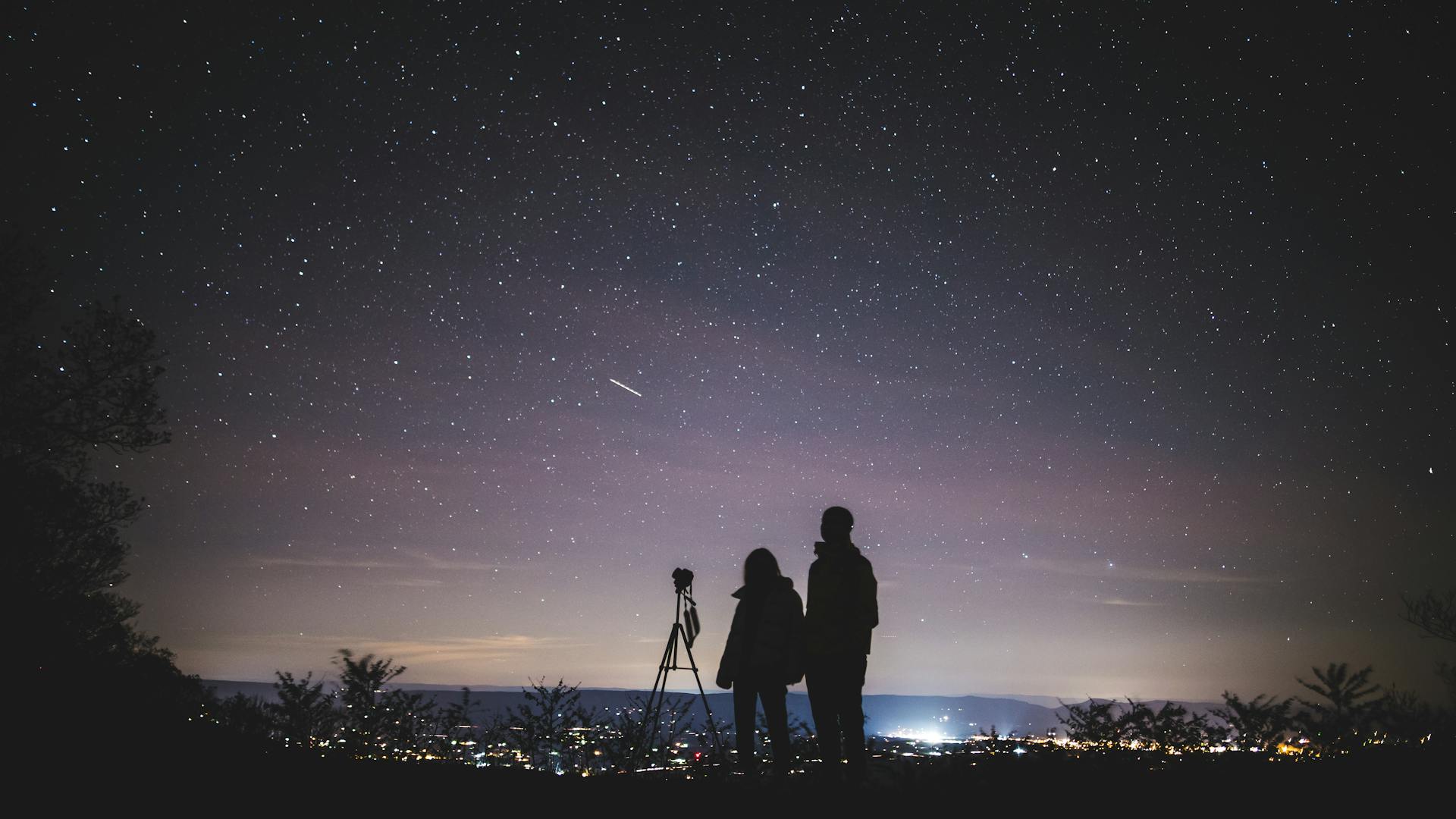 A couple sitting together under a starlit sky representing the emotional connection described by moon sign compatibility