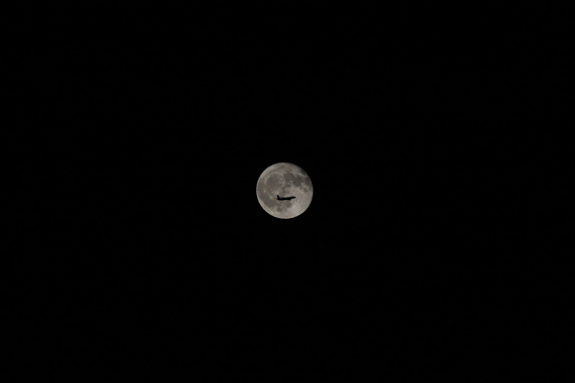 A glass jar of water sitting outside under a bright full moon, charging as moon water overnight