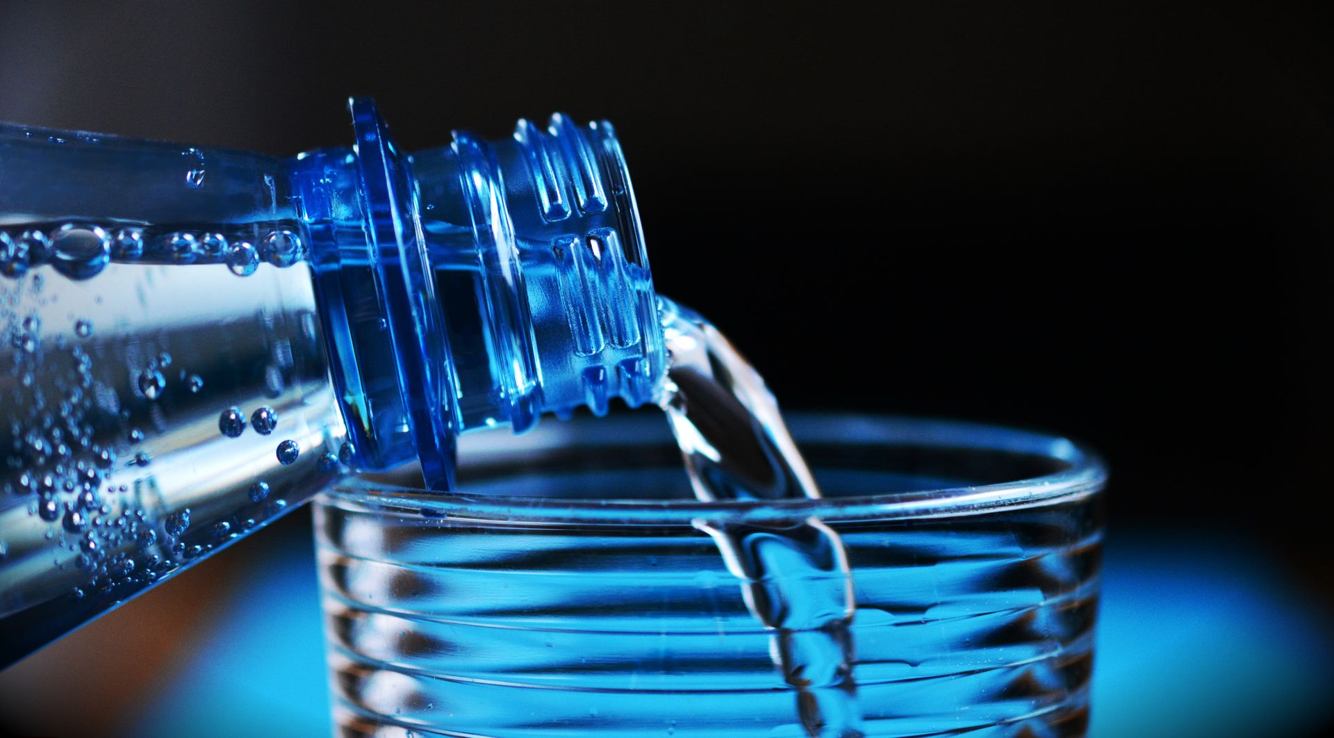A clear glass of water on a wooden table catching soft light, ready to be used as charged moon water