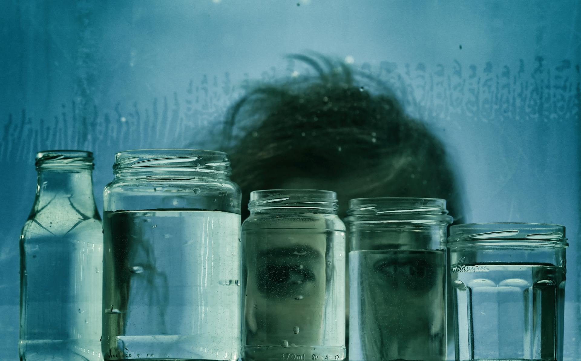 A glass jar of water glowing softly in moonlight on a windowsill