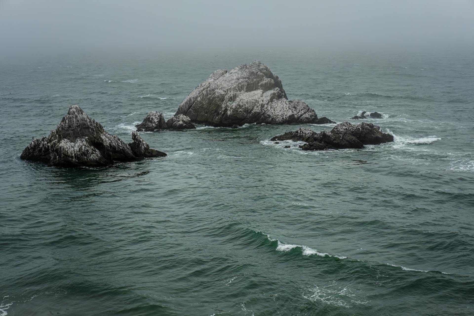 Peaceful ocean scene with eroded rocks shrouded in mist representing Neptune's dissolving of boundaries between the seen and unseen
