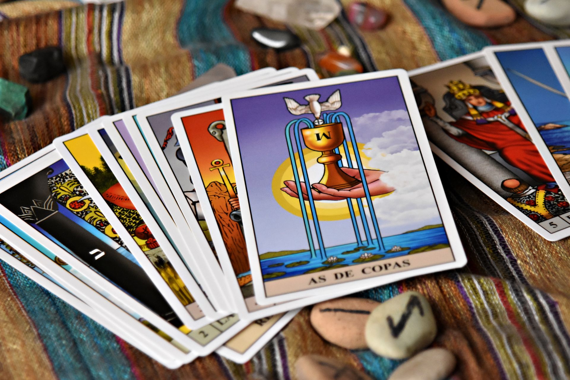 A set of oracle cards spread across patterned fabric beside crystals, illustrating simple beginner card spreads