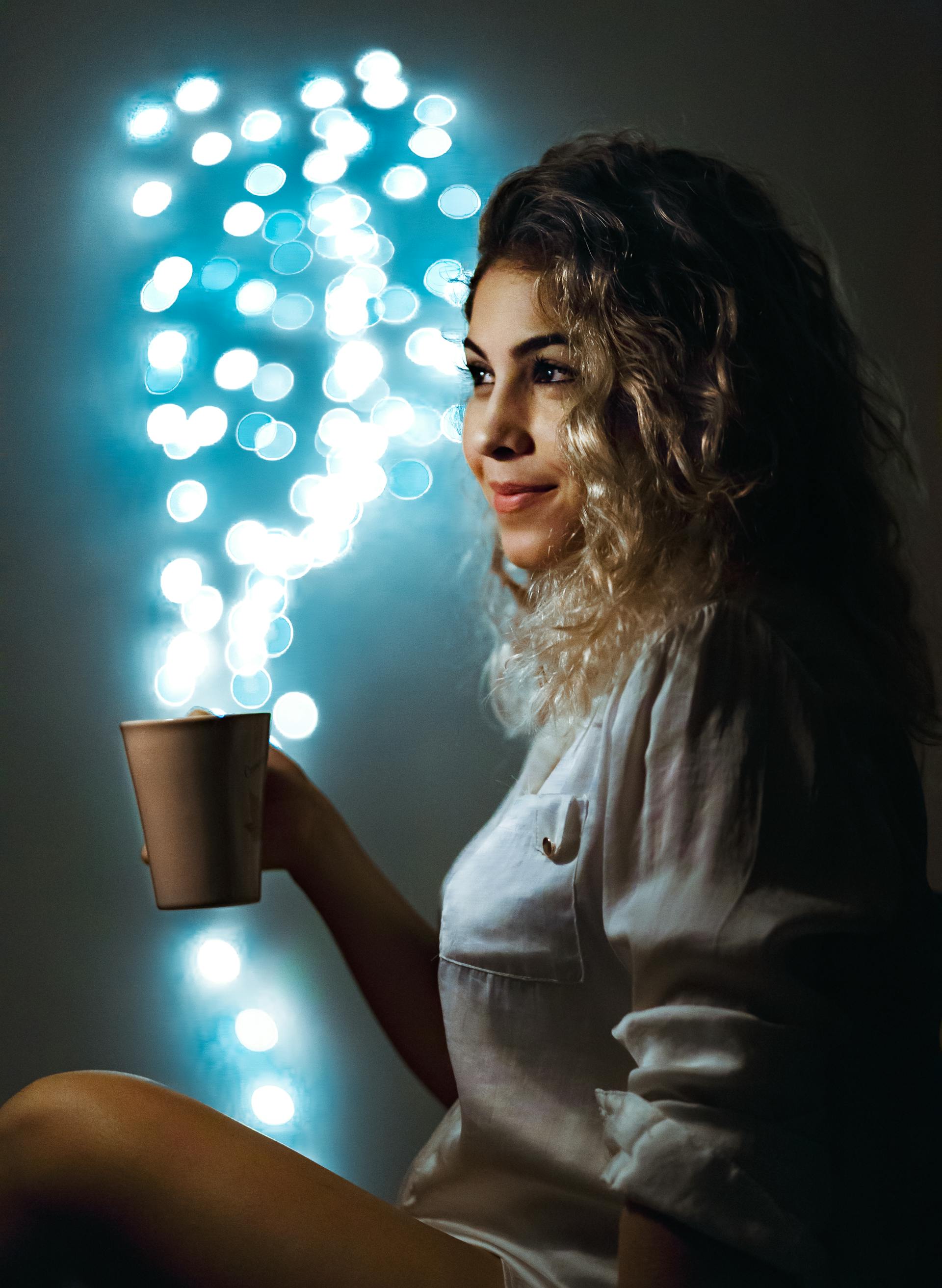 A woman enjoying a moment surrounded by twinkling lights creating a magical dreamy atmosphere that captures the creative and intuitive wonder of the Page of Cups