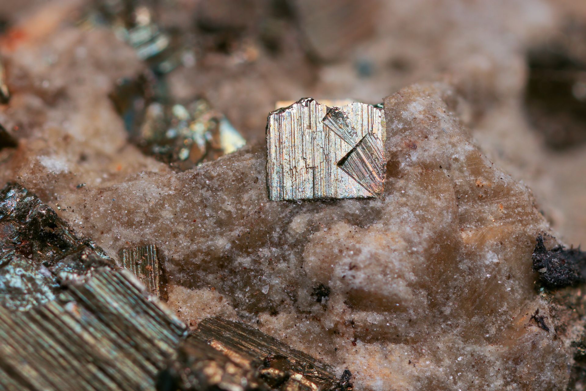 A brass-gold pyrite crystal with fine striations resting on pale quartz rock, showing the metallic shine behind pyrite meaning