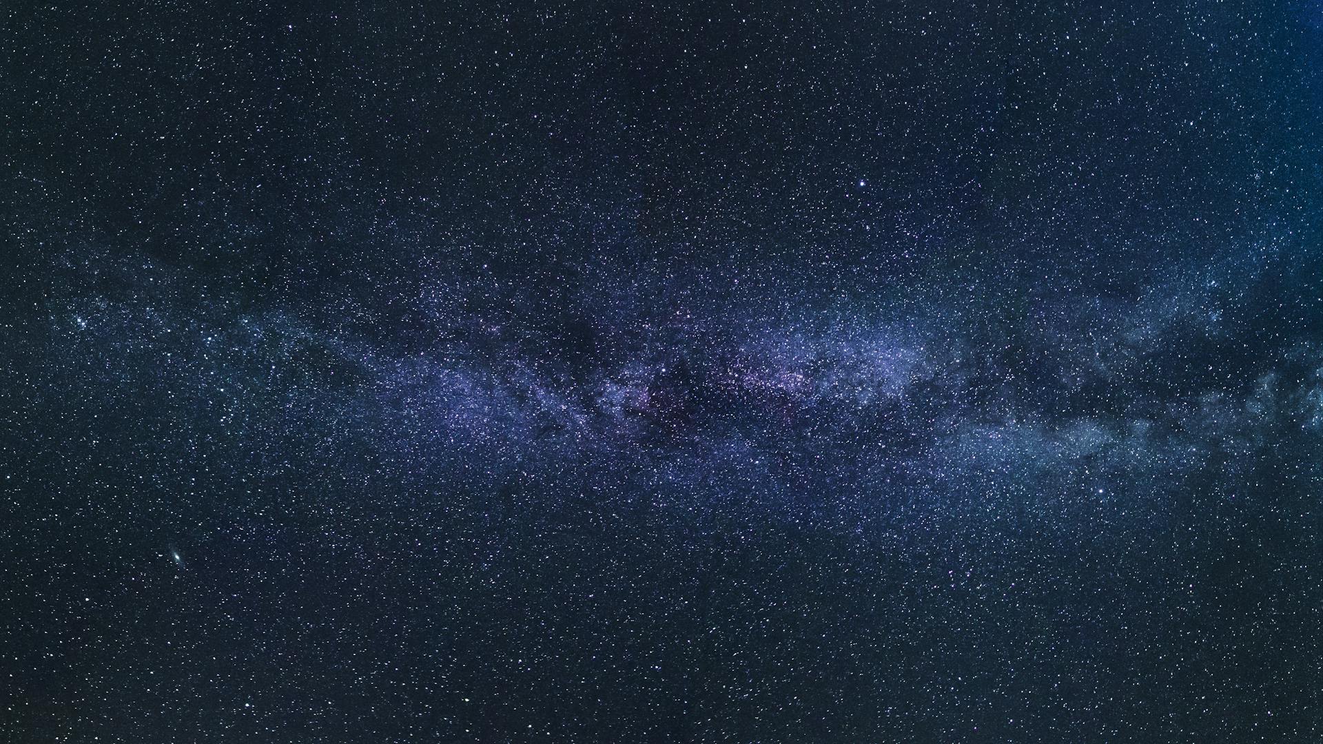 The Milky Way stretching across a vast starry sky over a silhouetted landscape