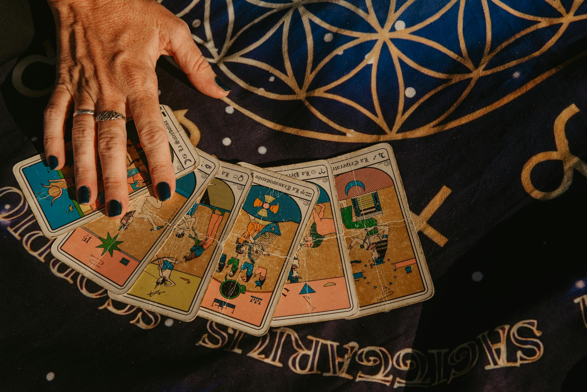 A hand arranging tarot cards on a star-studded cloth showcasing divination symbolism