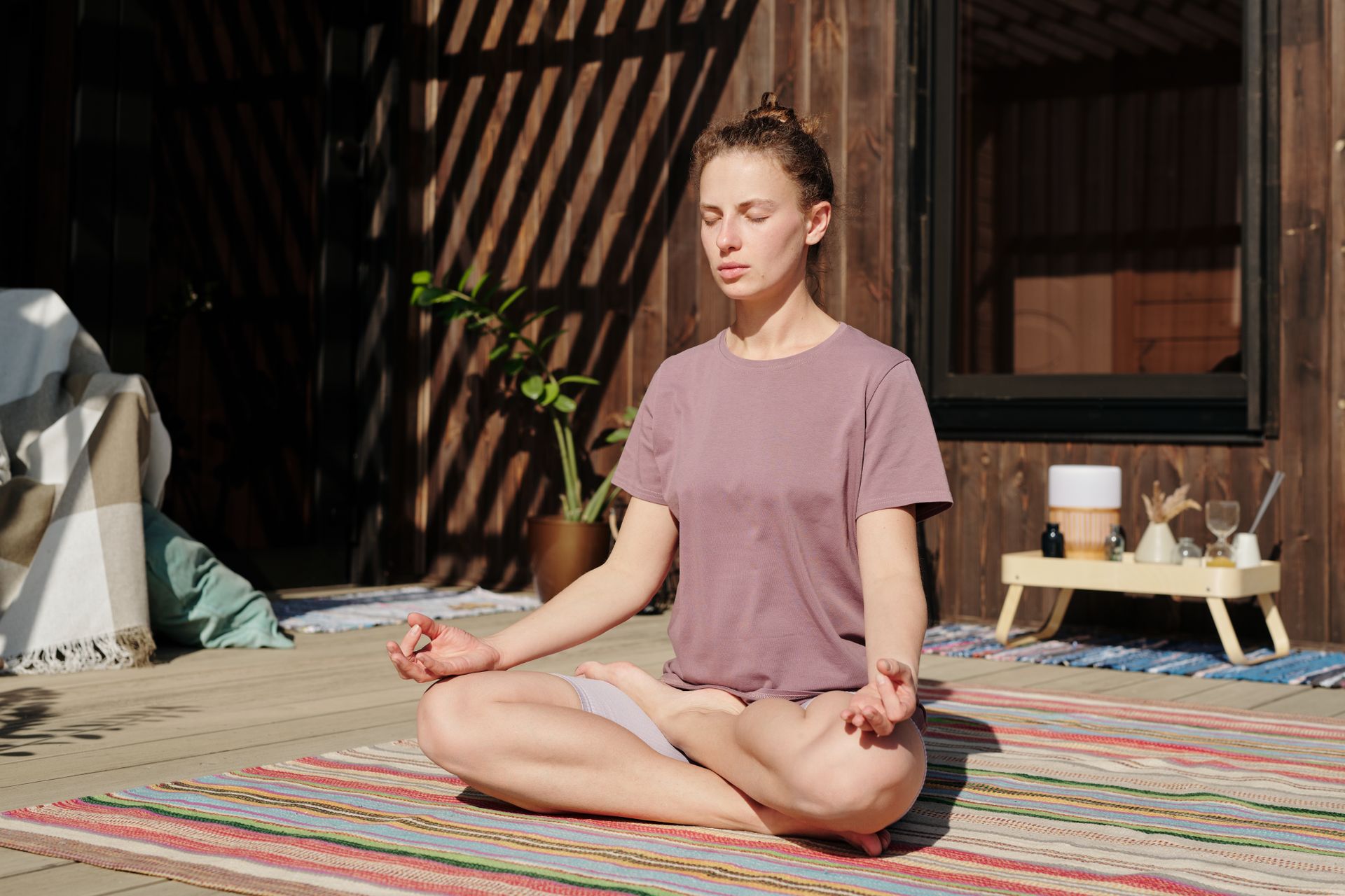 A woman sitting in lotus pose in soft outdoor light, grounded and calm, illustrating a balanced root chakra