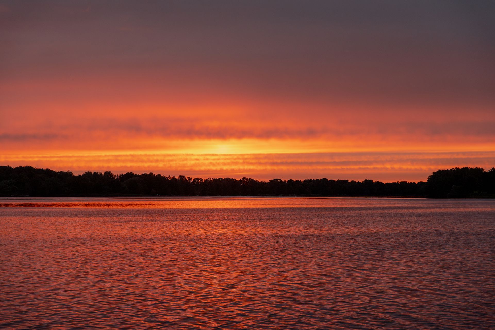 A vivid orange sunset reflecting across rippling water, echoing the orange color and water element of the sacral chakra